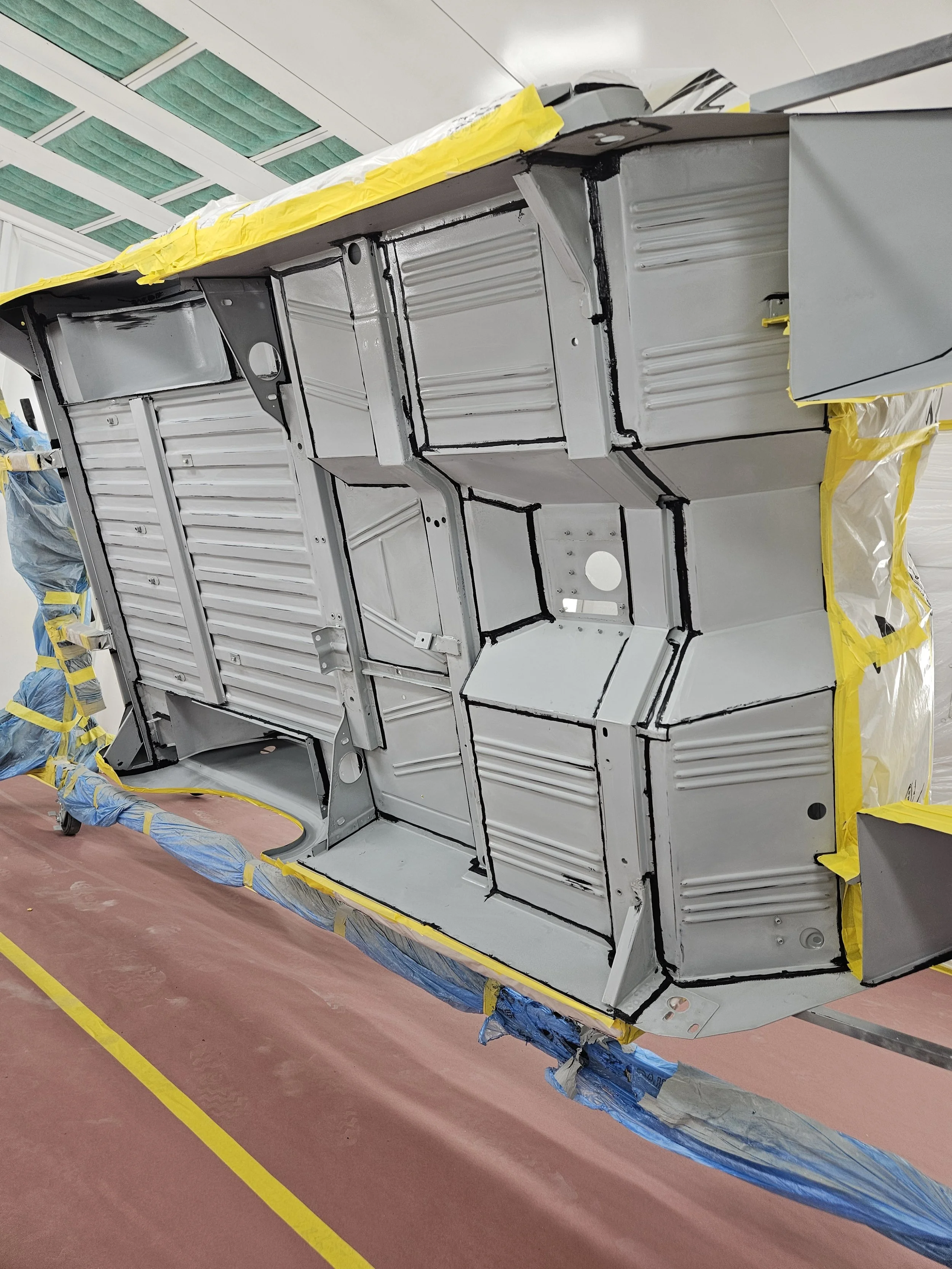 Close-up view of the interior structure of an aircraft's fuselage in a manufacturing or repair facility, with yellow and blue protective coverings and insulation materials visible.