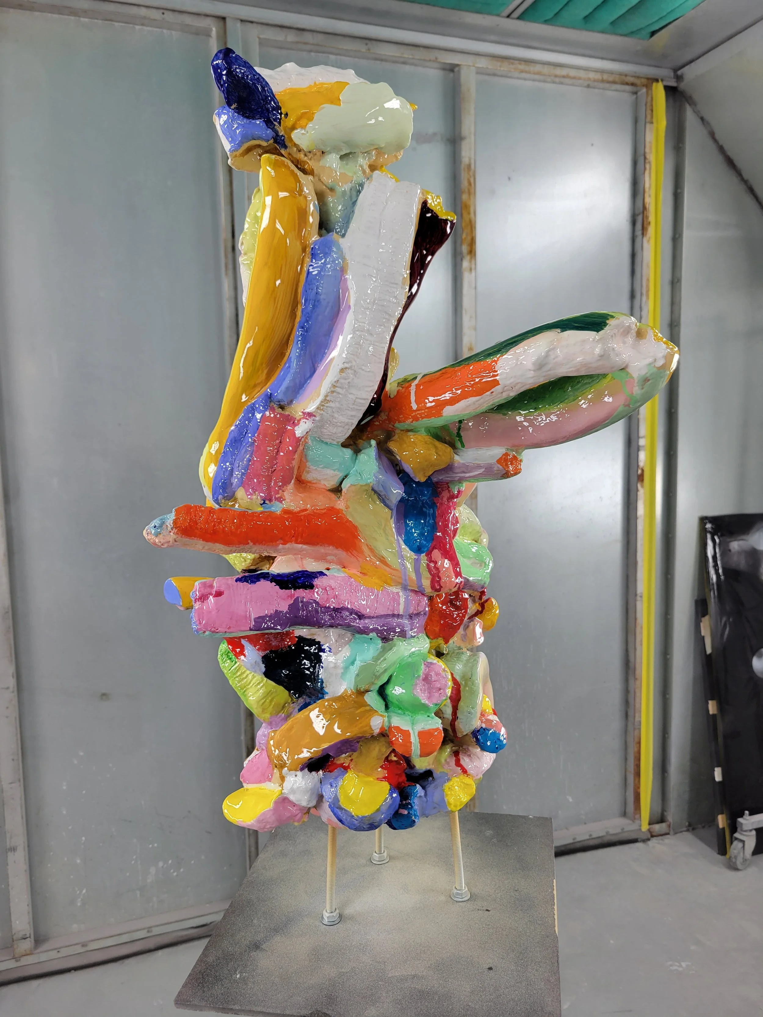 Colorful abstract sculpture with various bright, glossy painted shapes on a pedestal.