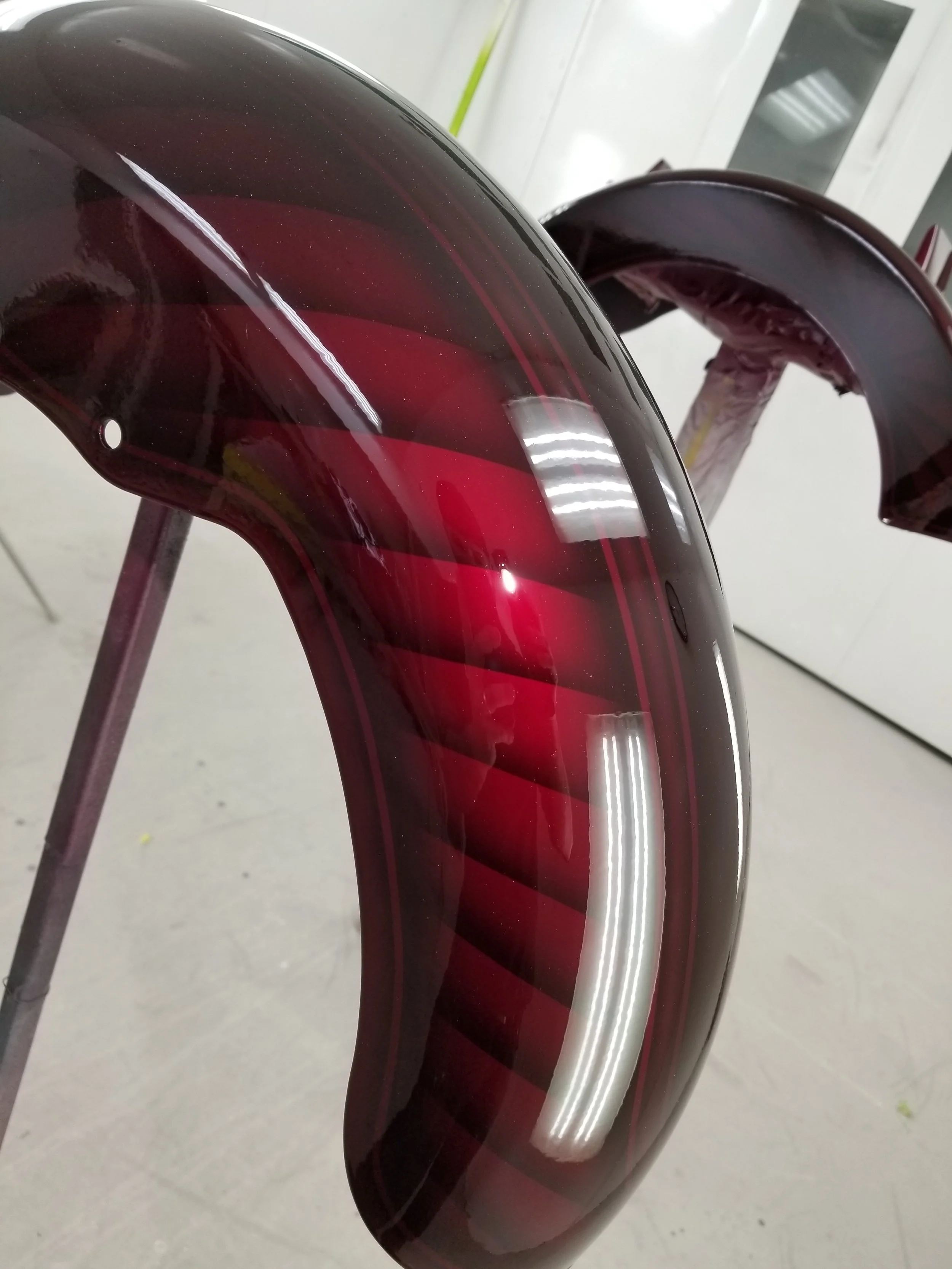 Close-up of a glossy, dark red, curved motorcycle part
