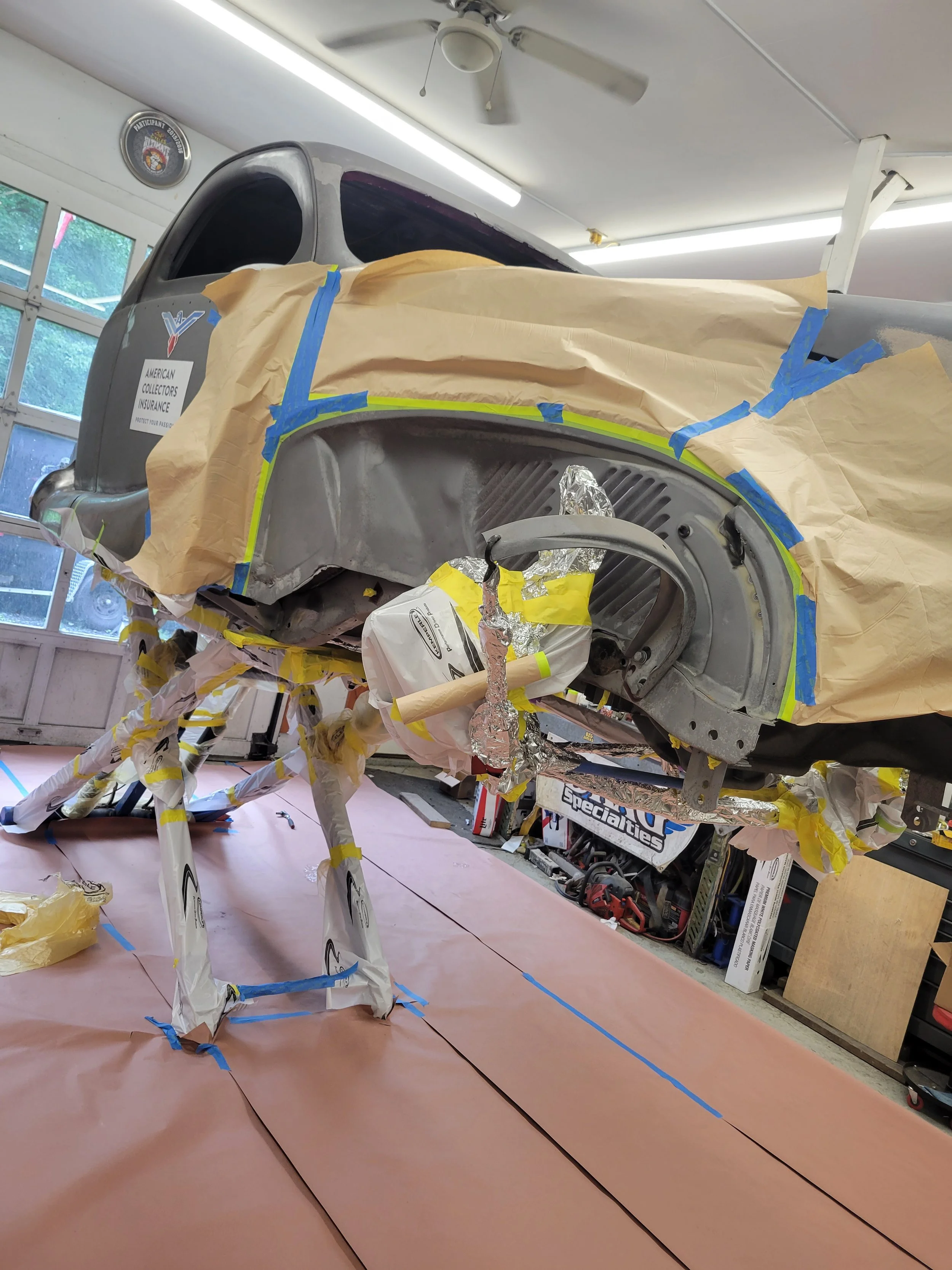 A car undergoing bodywork repair, elevated on stands in a garage.