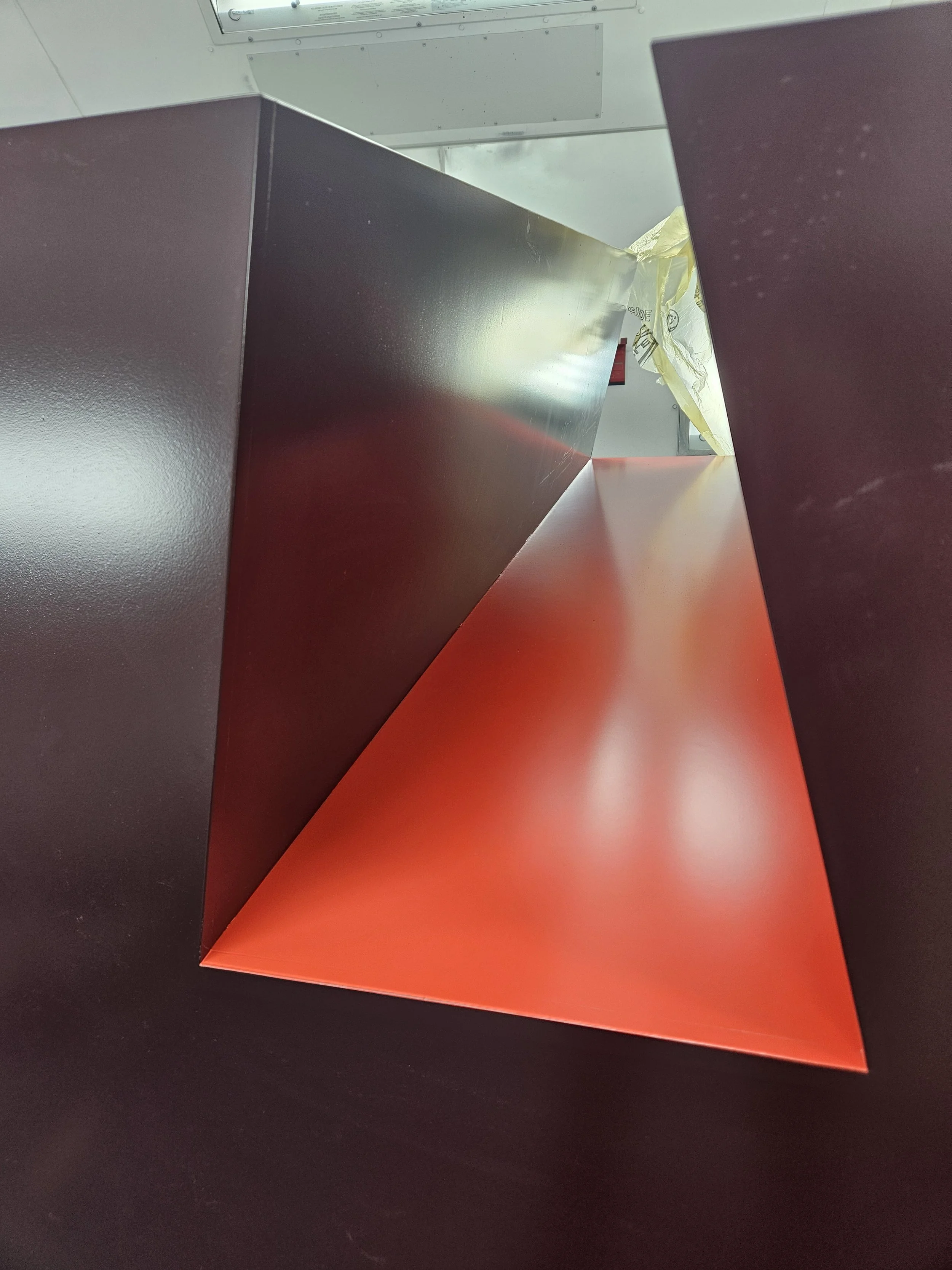Close-up of a modern, geometric art installation with black and red reflective surfaces forming a three-dimensional shape.