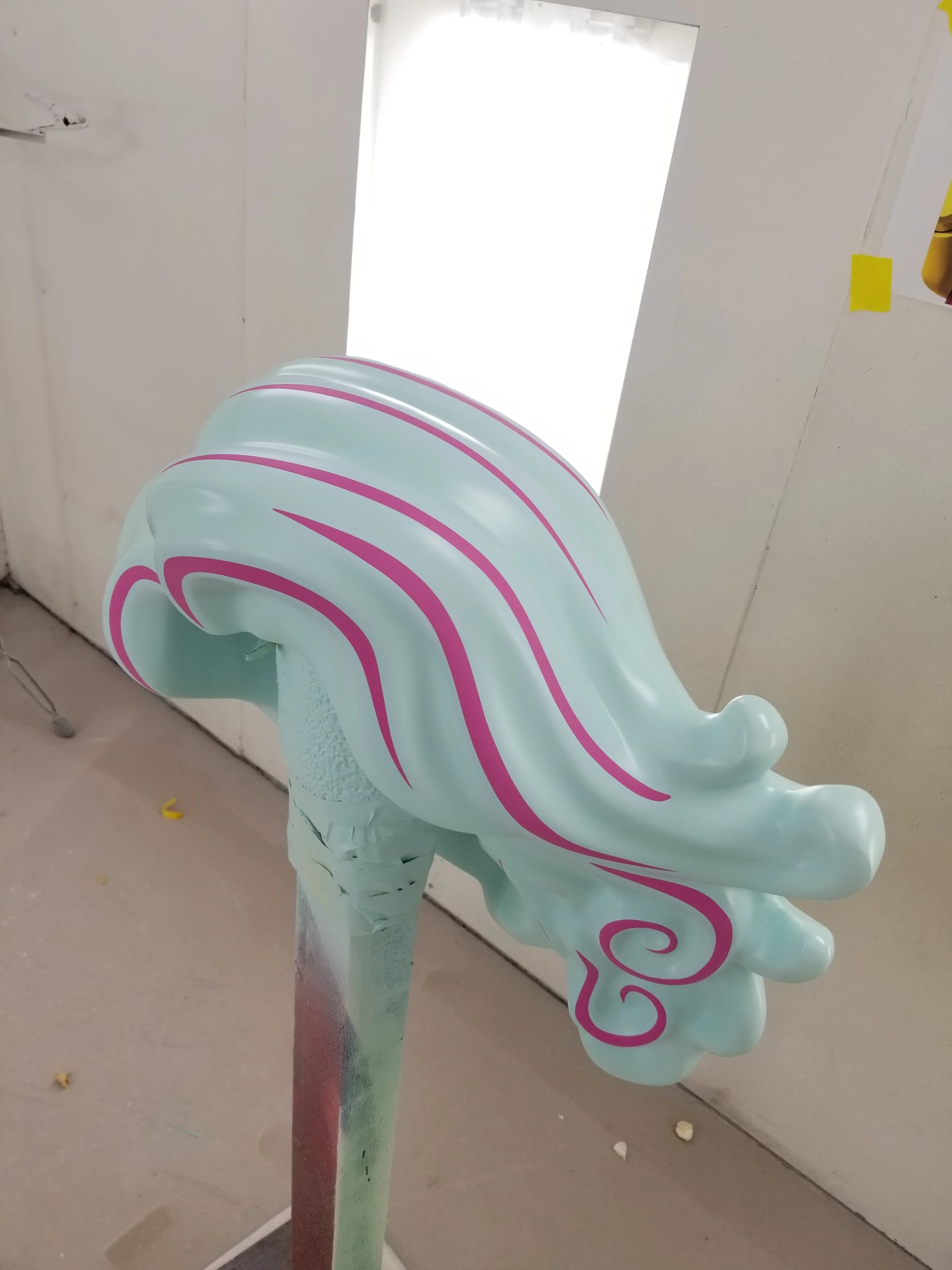 A pastel-colored sculpture LEGO hair, mounted on a stand.
