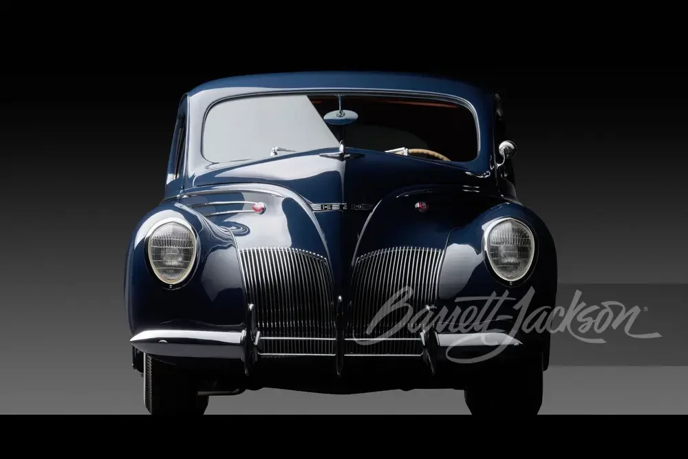 A classic black vintage car with rounded features and prominent front grille, set against a dark background.