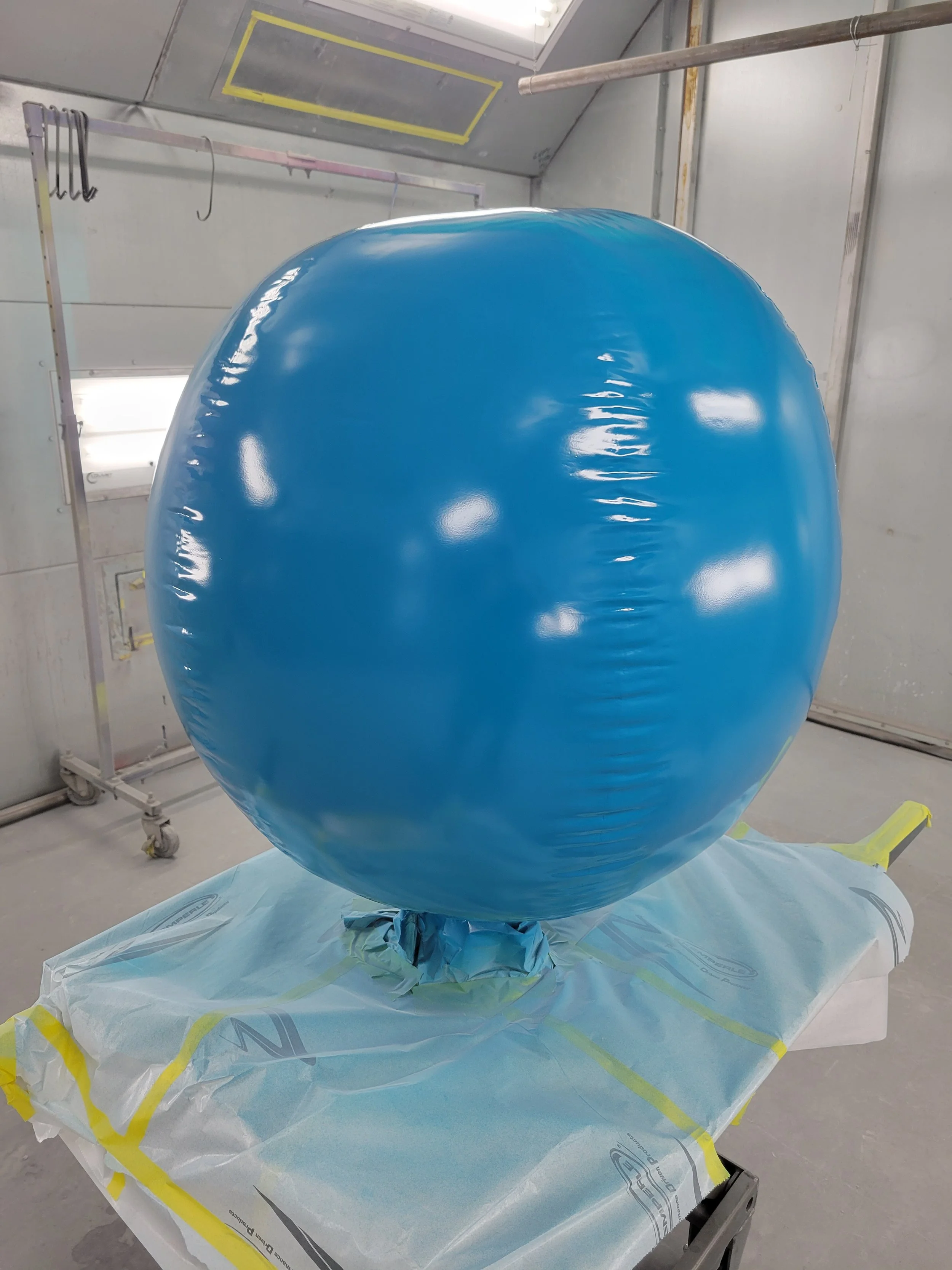 A large blue inflatable sphere in a tunnel-like, industrial setting, positioned on a table covered with a protective sheet.