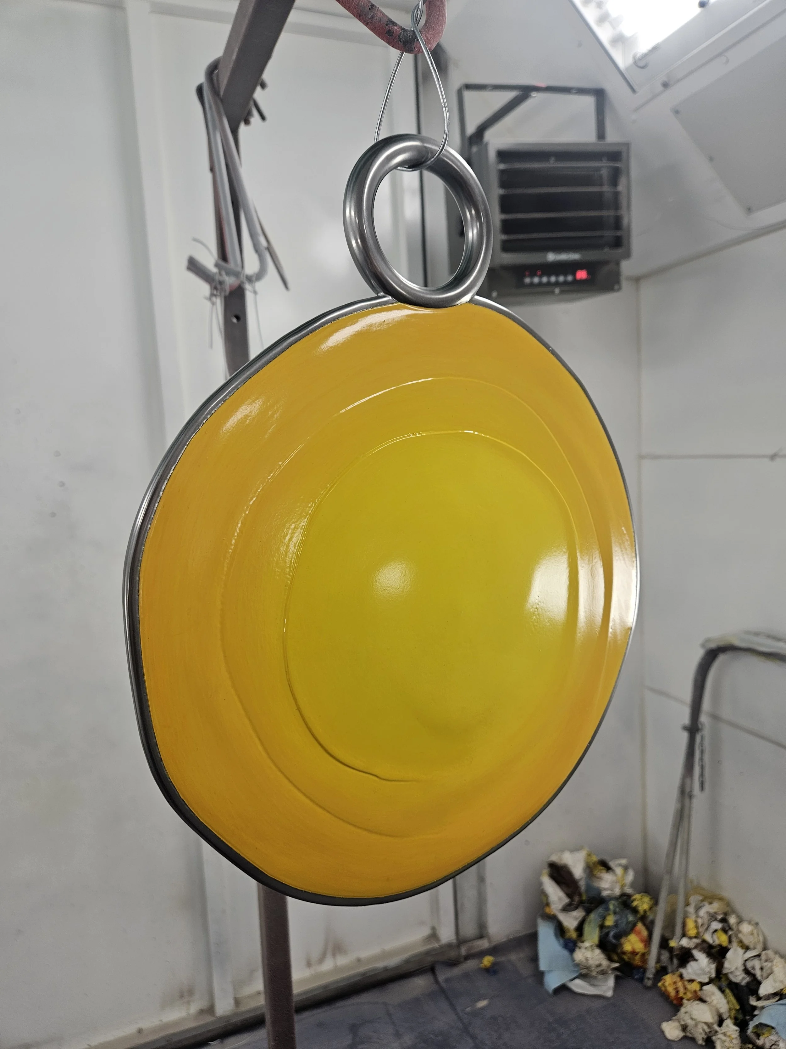 Yellow enamel camping bowl hanging on a hook in a kitchen setting.