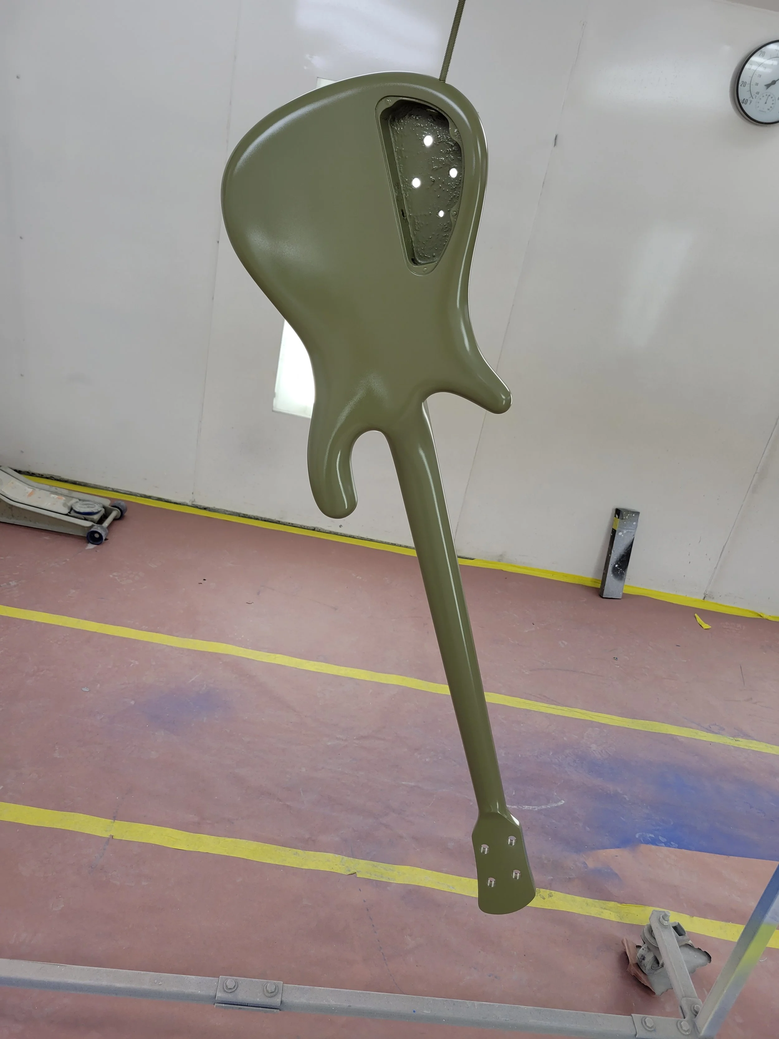 A large, green, abstract sculpture resembling a stylized fish with a transparent section containing bubbles.