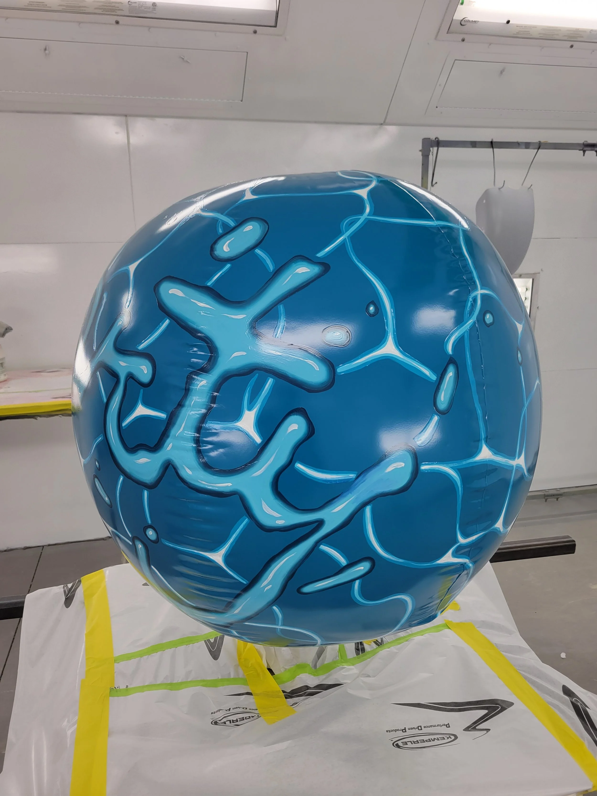 A spherical object with a blue surface featuring white and darker blue abstract lines and shapes, set indoors.