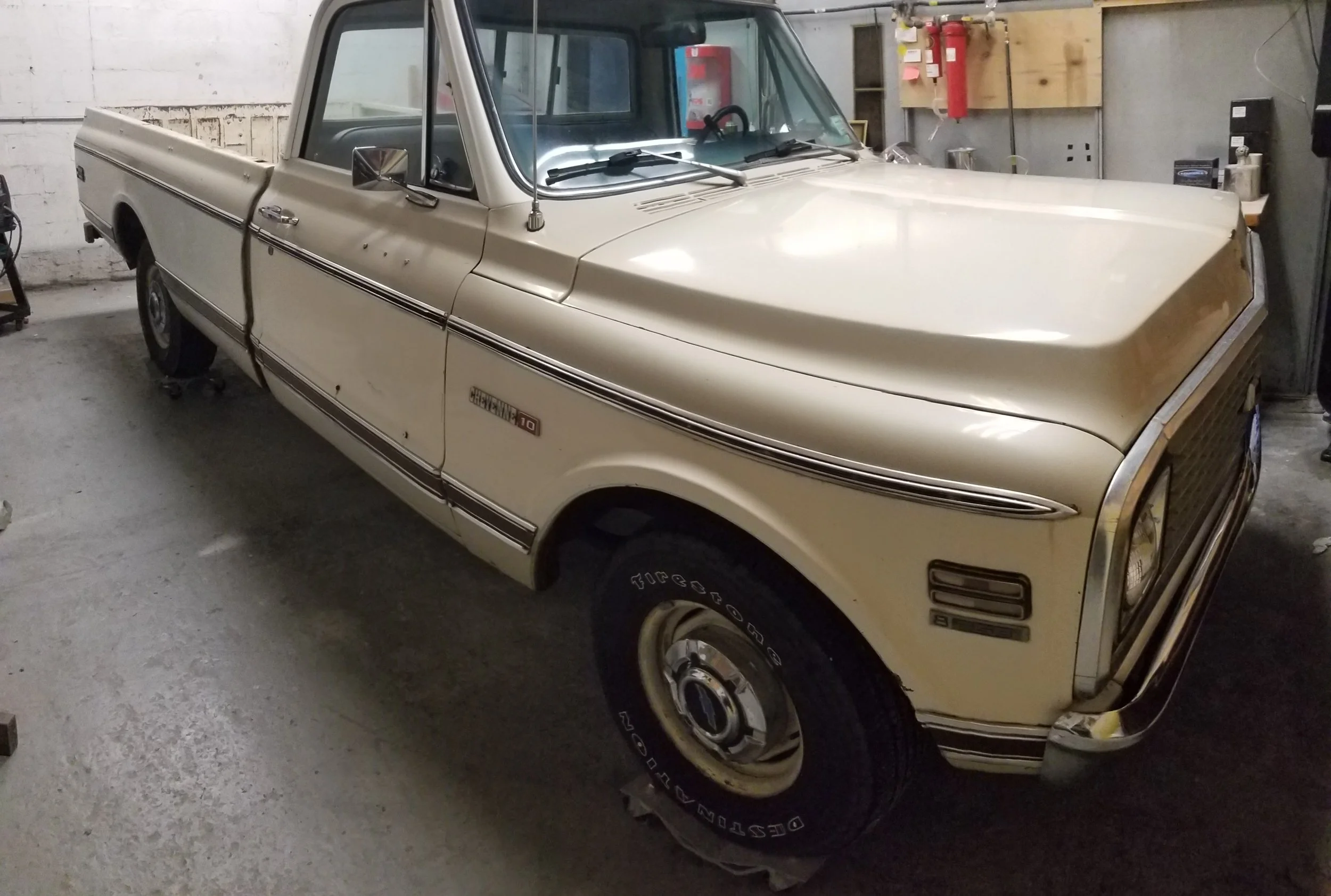 A vintage beige pickup truck parked inside a garage.