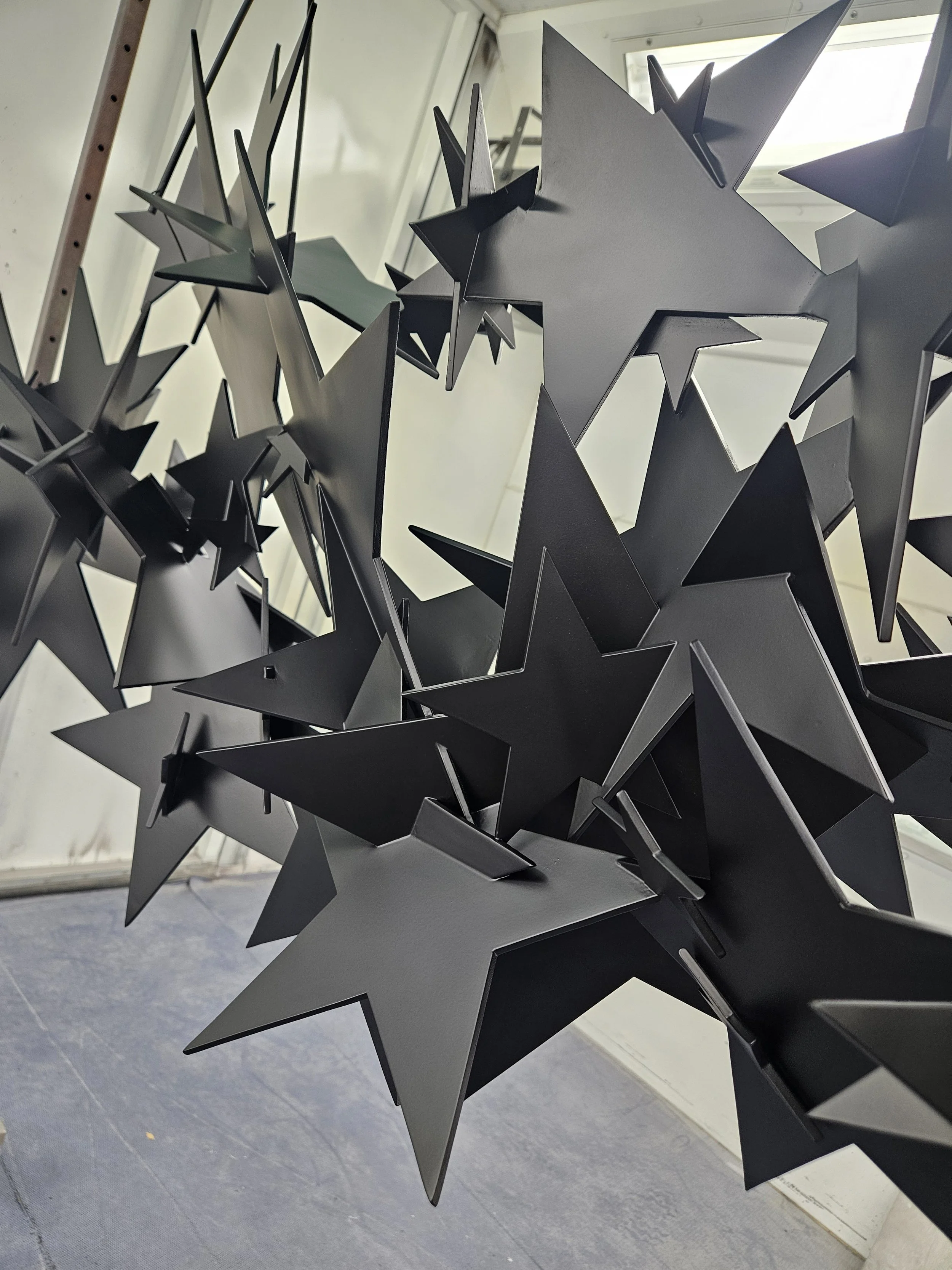 Close-up of multiple black star-shaped sculptures attached to a metal frame.