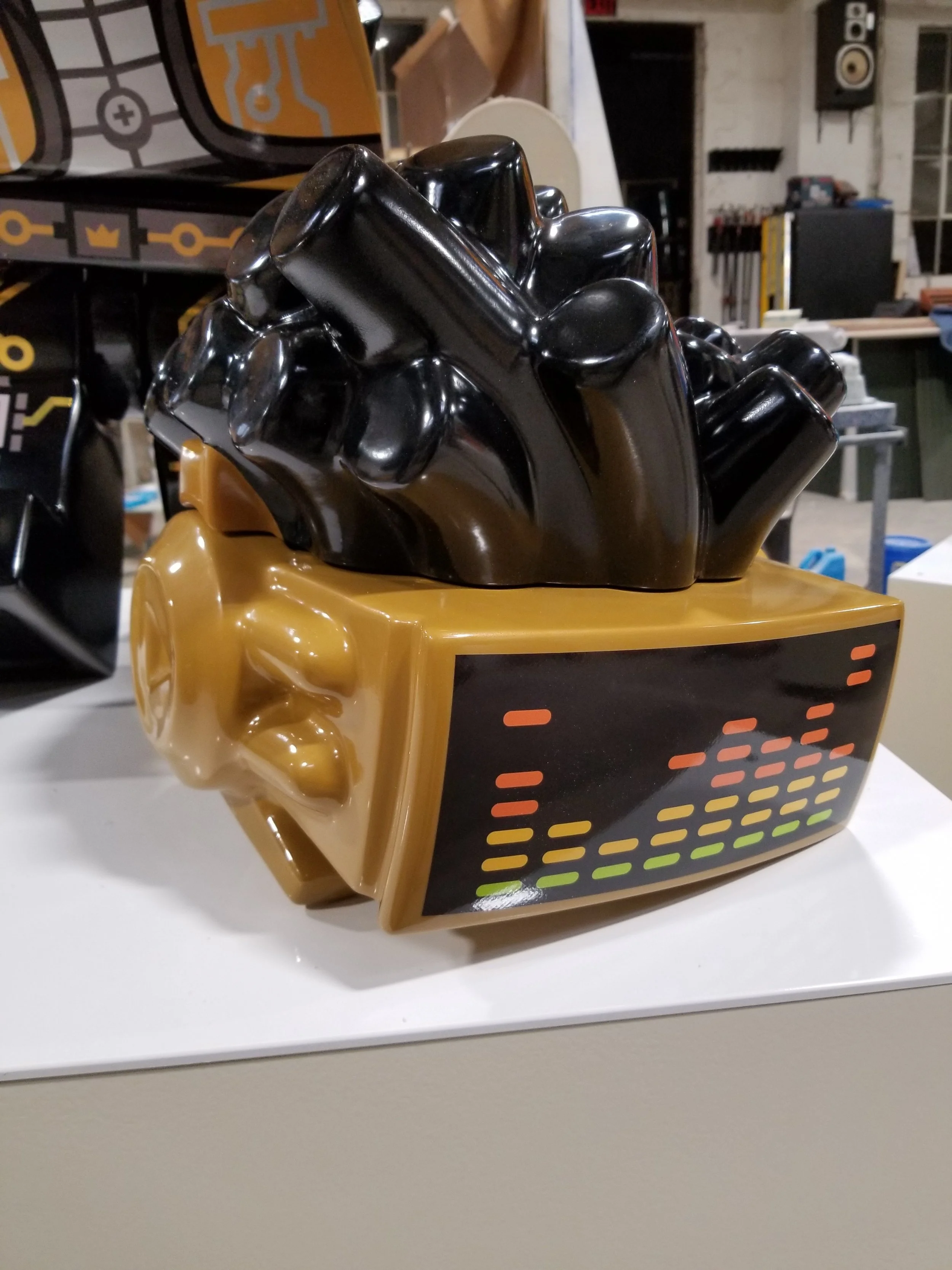A sculpture of a LEGO figure designed in a retro style with a gold-colored base and a digital equalizer display on the front.