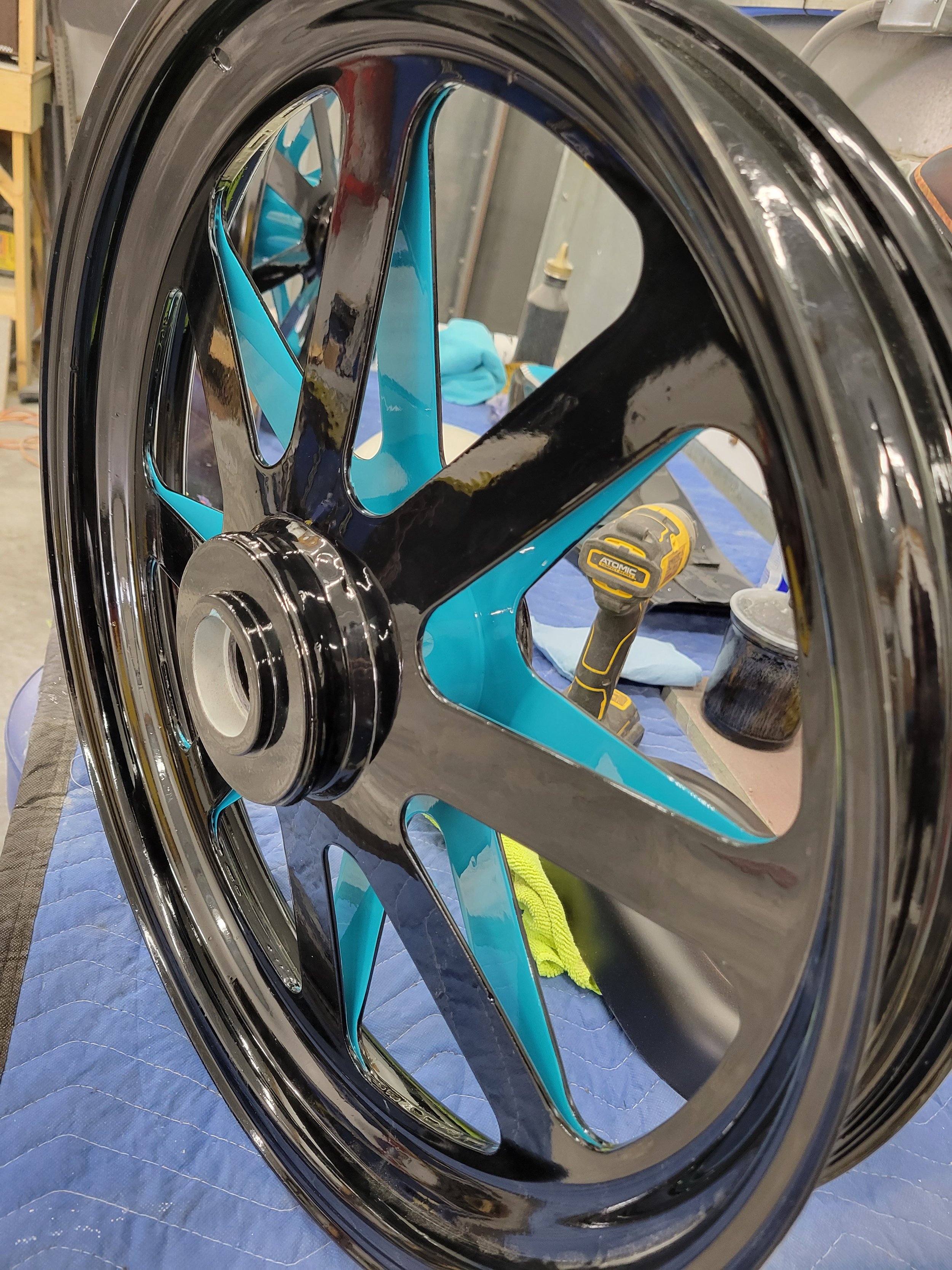 Close-up of a black and blue bicycle wheel with a wrench and tools in the background.