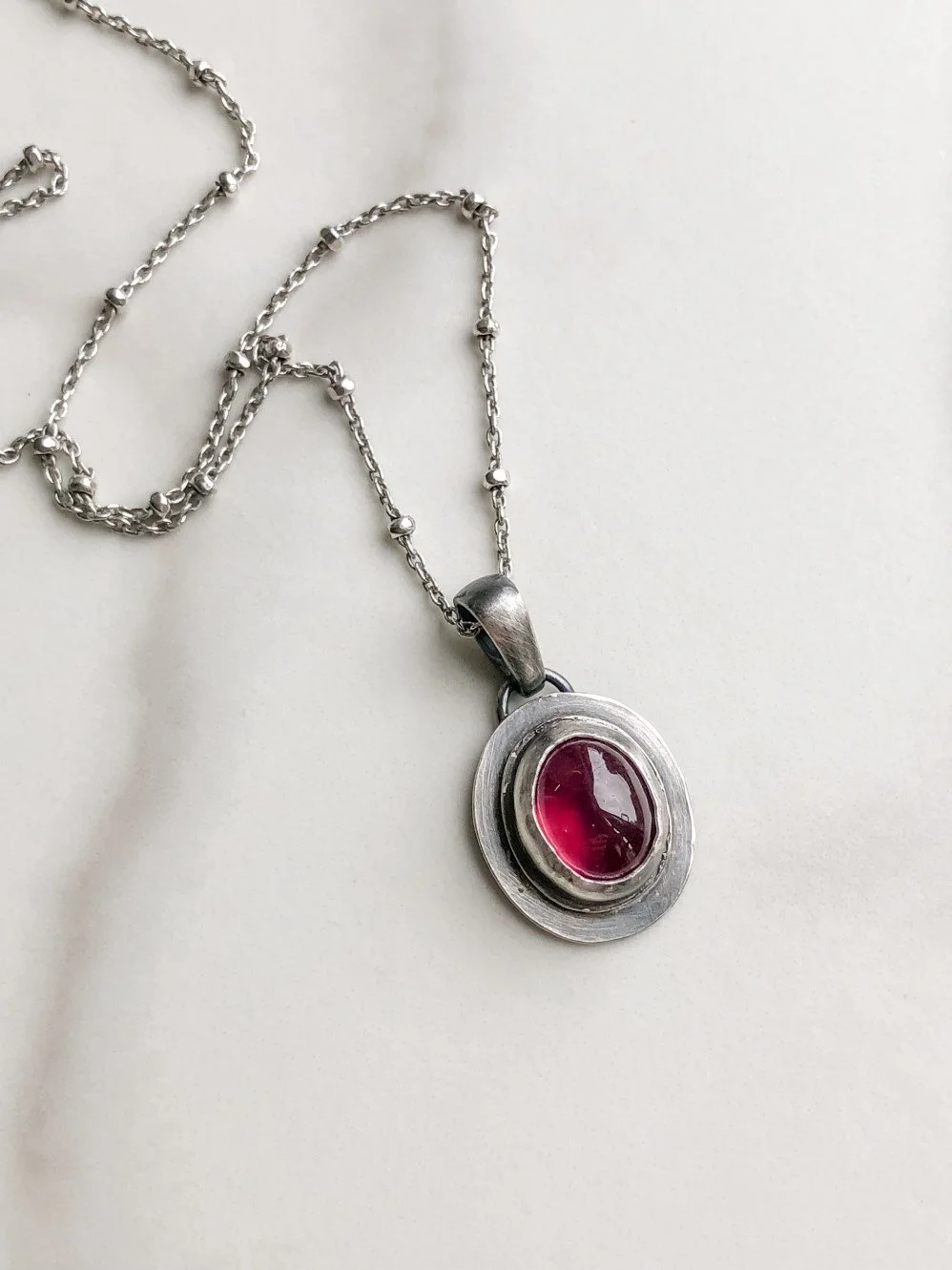 Oval red ruby on flat  silver pendant on a ball chain