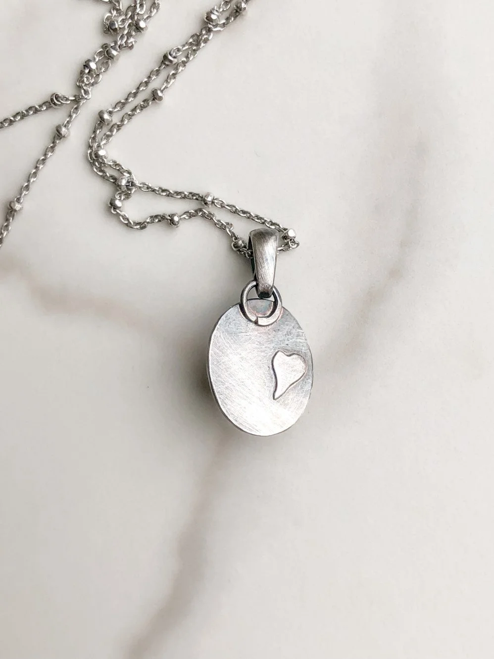 Heart detail on the back of the silver pendant