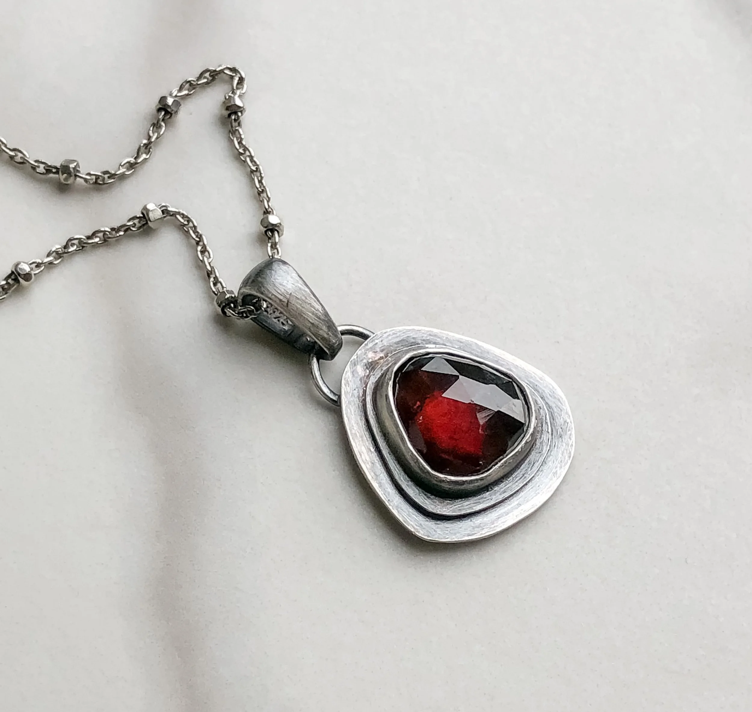 Red ruby rounded triangle shape on flat  silver pendant on a ball chain