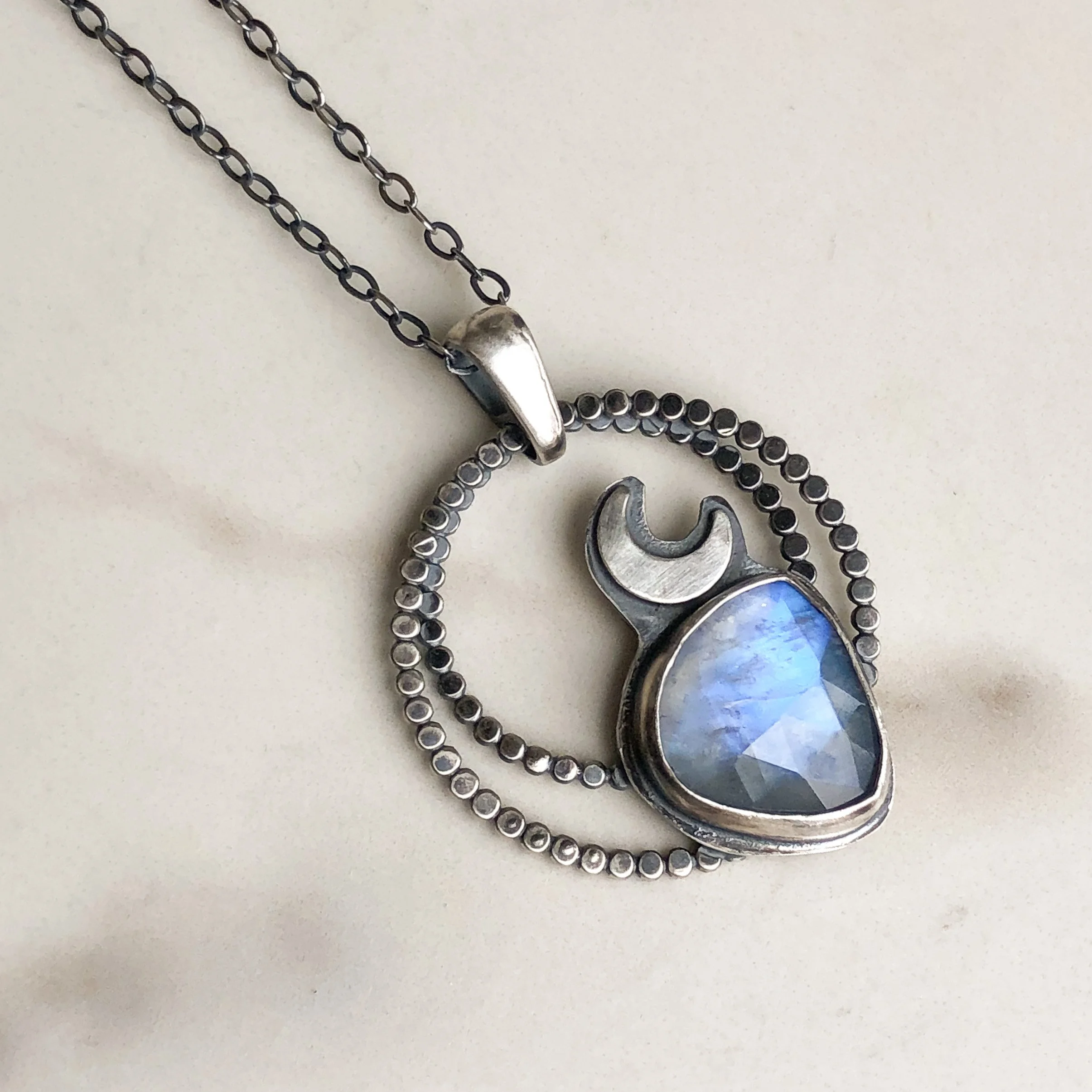 Moonstone necklace with silver crescent accent set on a concentric circle pendant