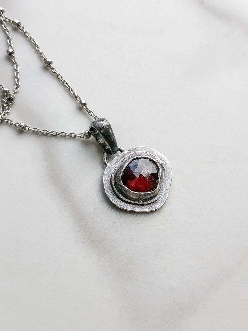 Natural shape red ruby on flat  silver pendant on a ball chain
