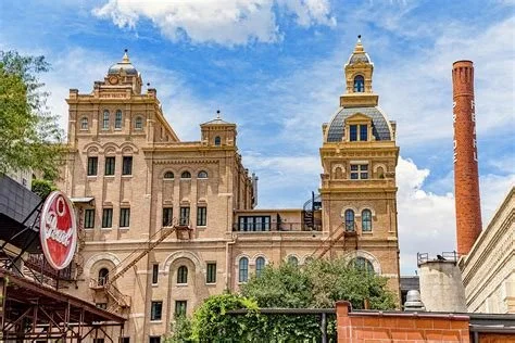 Historic building with ornate towers and a red brick chimney under a partly cloudy sky.
