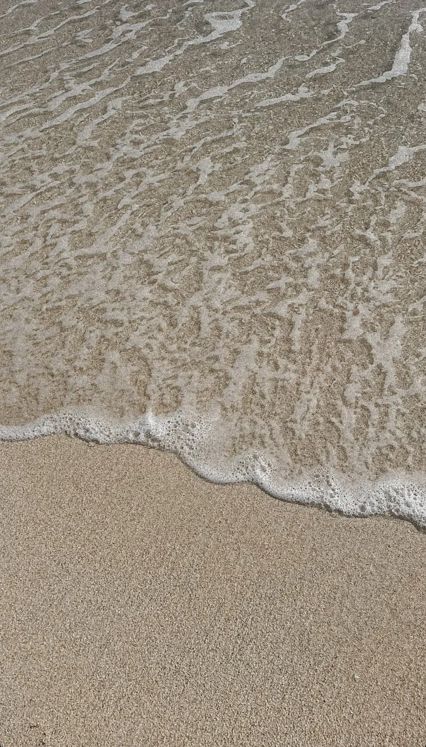 Close-up of sandy beach with gentle ocean waves washing onto the shore.