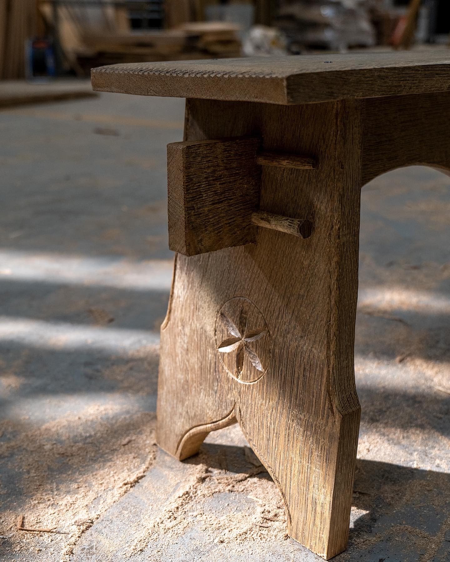 Close-up of a wooden bench in a woodworking workshop, showing the carved star design on the side.