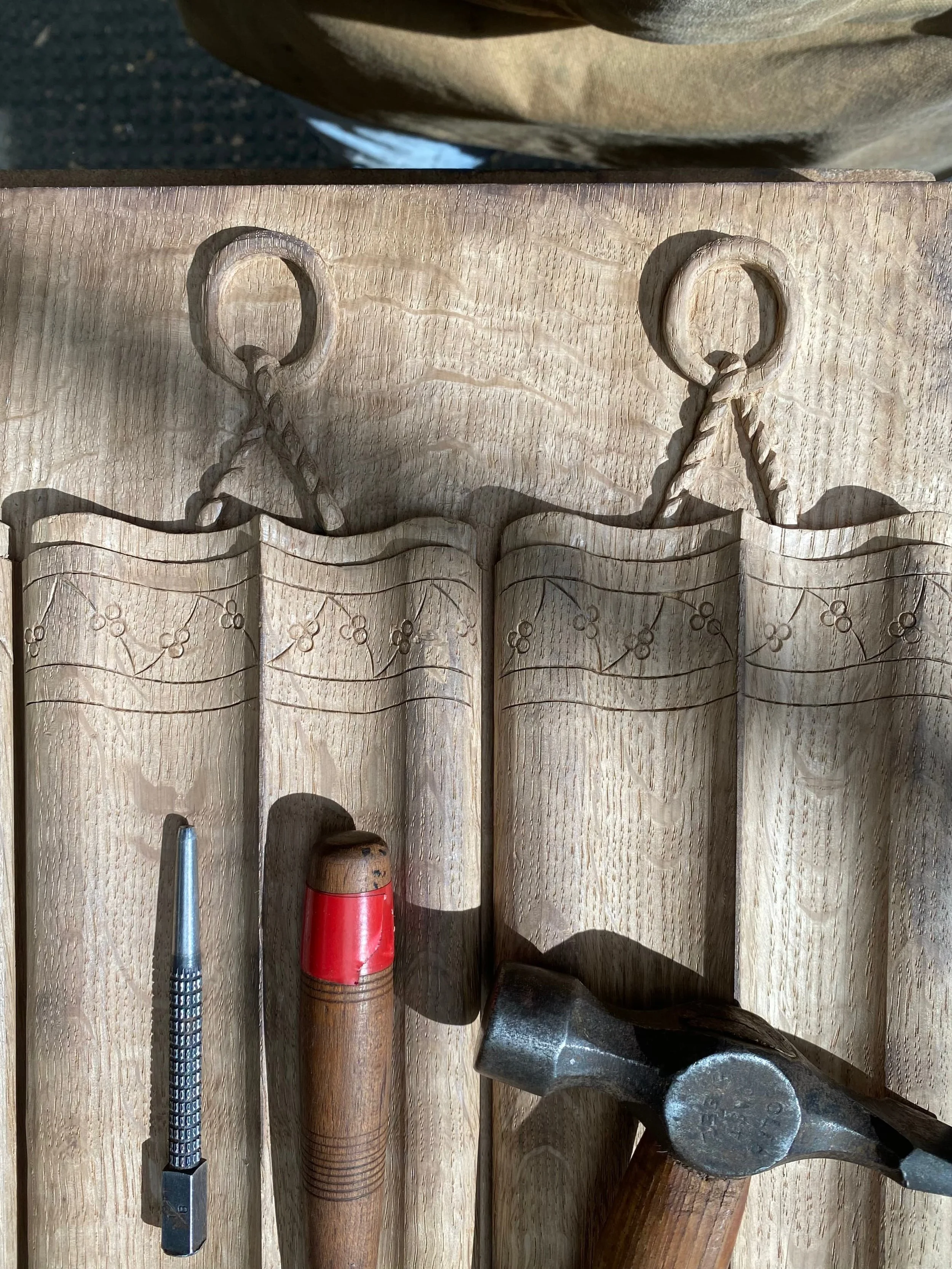 Tools placed on a wooden surface, including a screwdriver, a wooden-handled tool, a hammer, and other hardware.