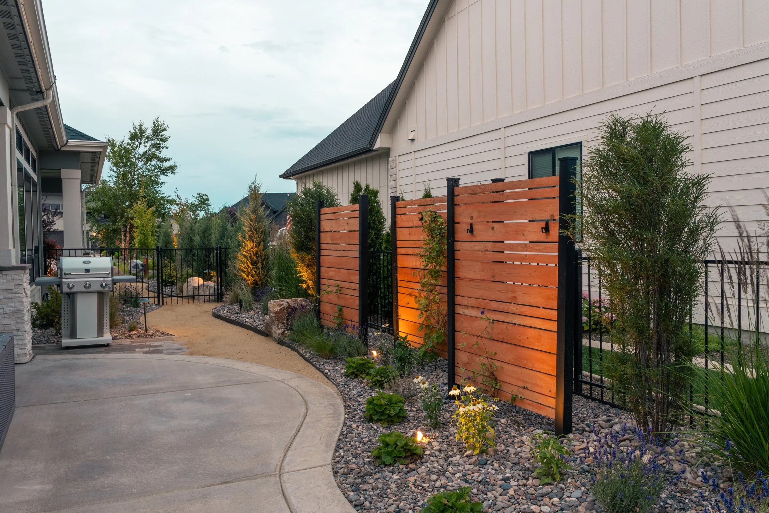 Curved garden pathway leading through layered planting and privacy screening in a residential landscape in Star, Idaho.