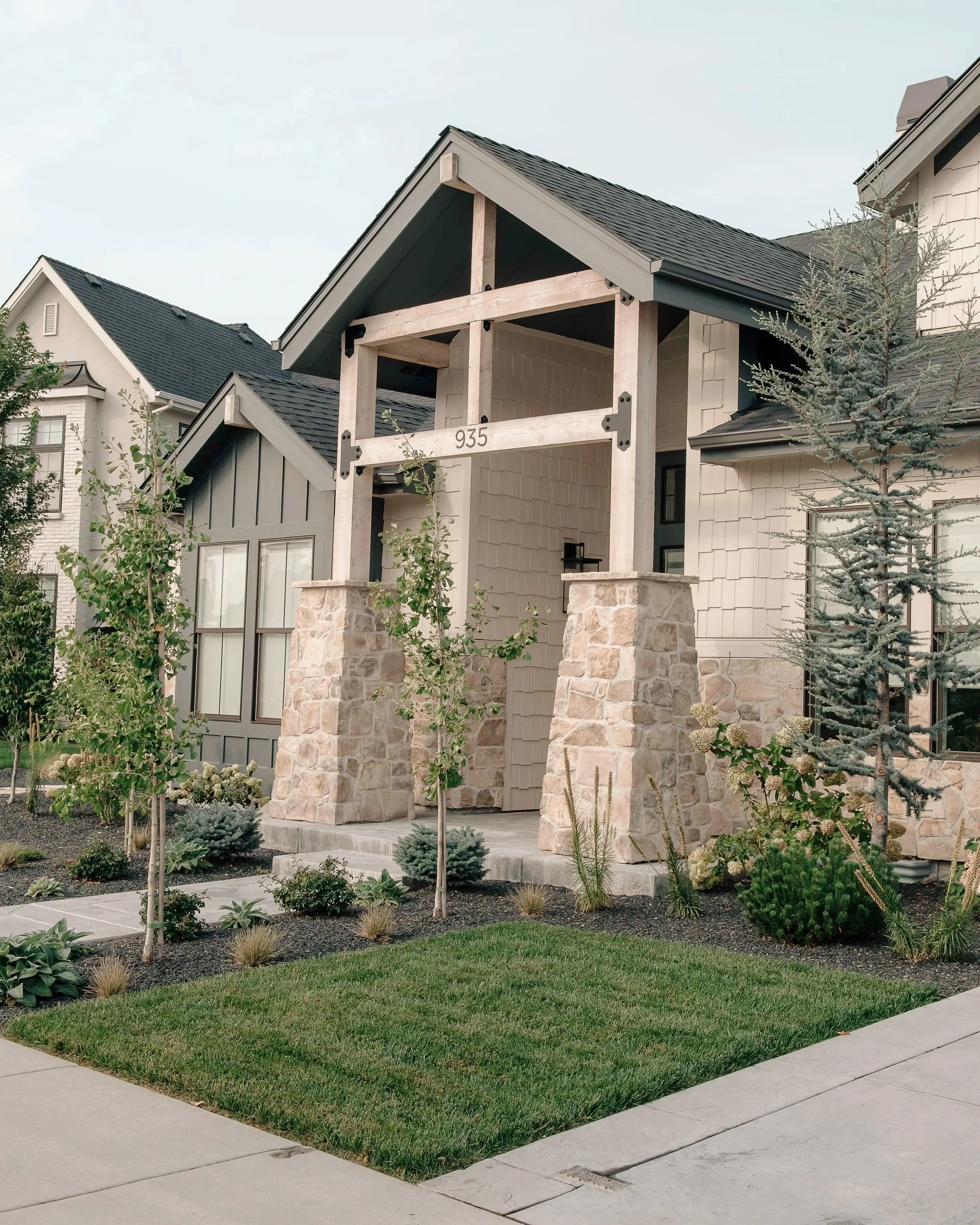 Professional landscape design in Boise Idaho featuring modern front yard landscaping, layered shrubs, young trees, and natural stone accents.