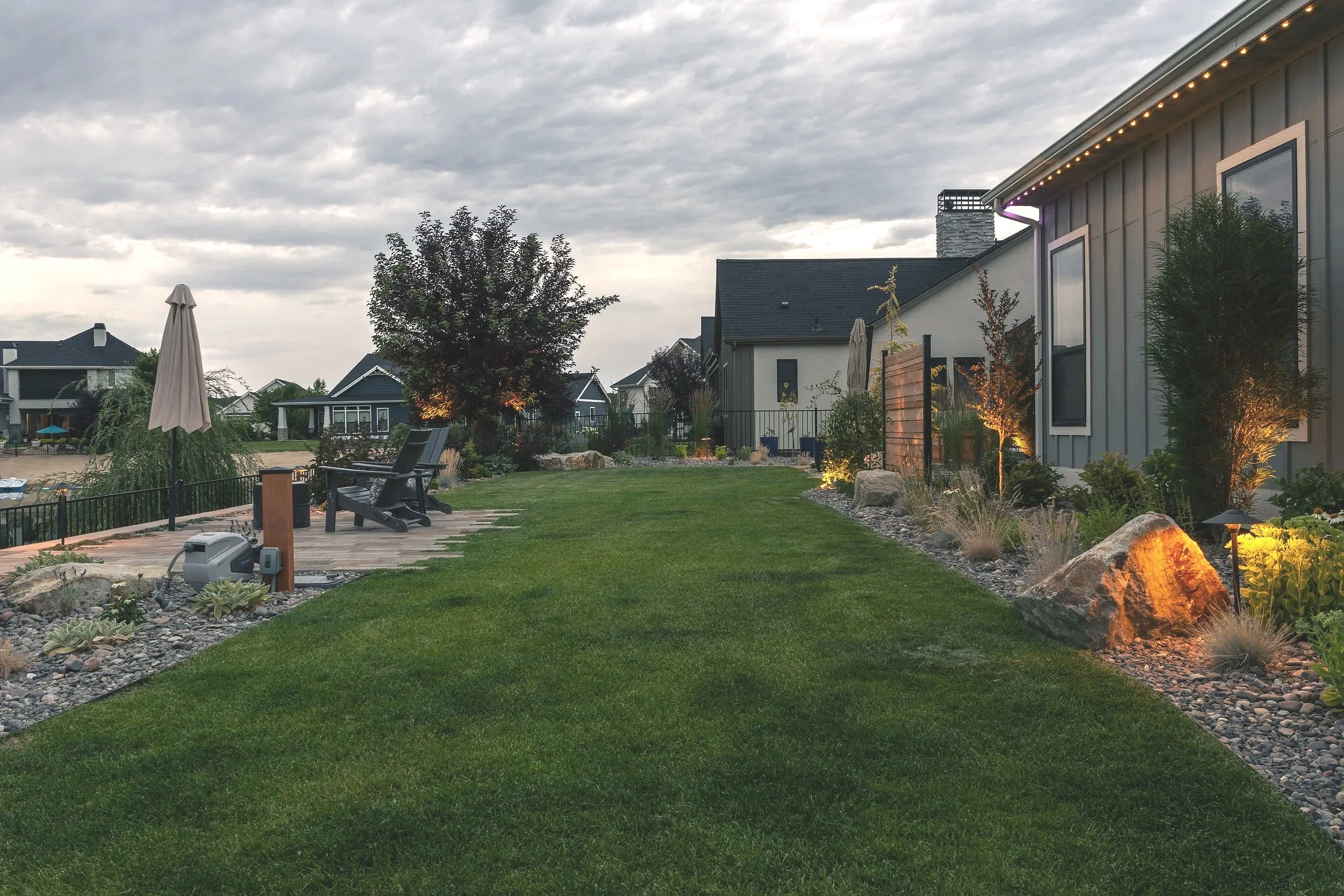 Evening landscape lighting illuminating planting beds, privacy screening, and a garden pathway in a residential landscape in Star, Idaho.