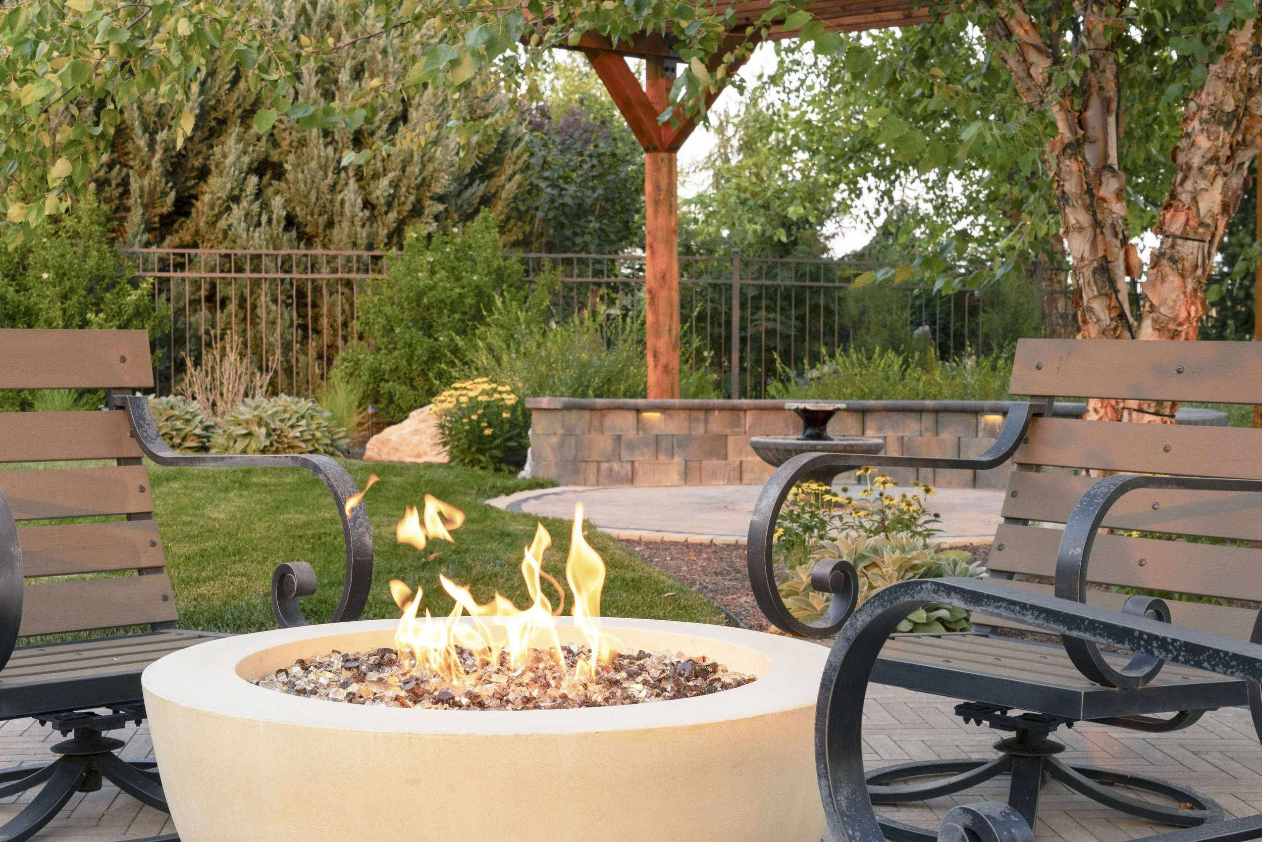 Luxury outdoor living space in Eagle, Idaho featuring a natural stone fire pit, covered pergola, and professionally designed landscape by Kanvas Landscape Design.