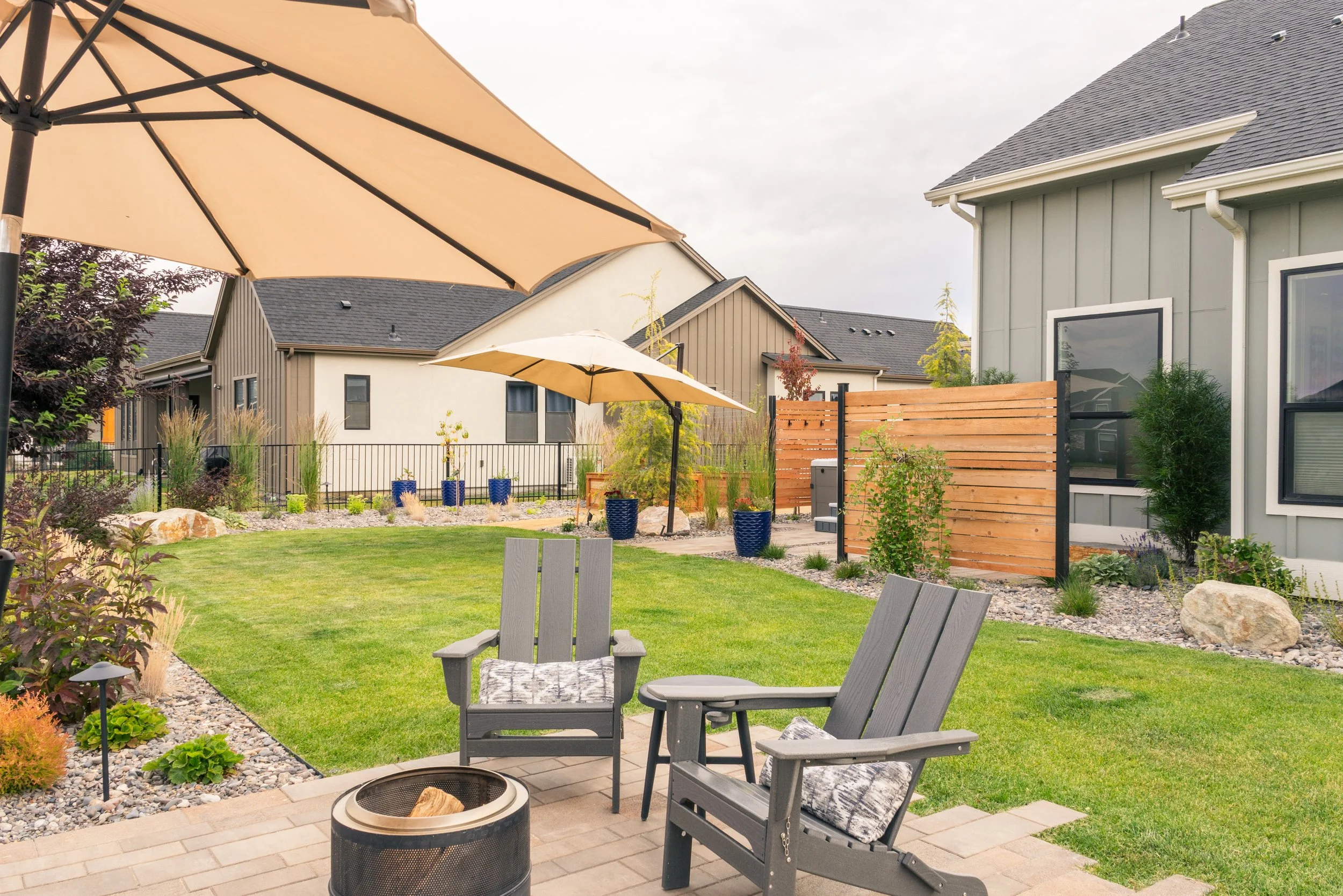 Outdoor living patio with umbrellas providing shade in a thoughtfully designed residential landscape in Star, Idaho.