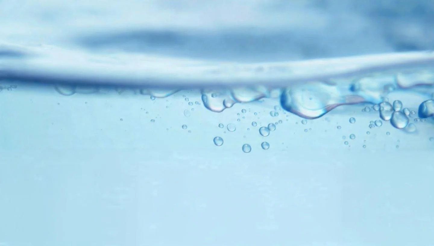 Close-up of water with bubbles and a wave on the surface.