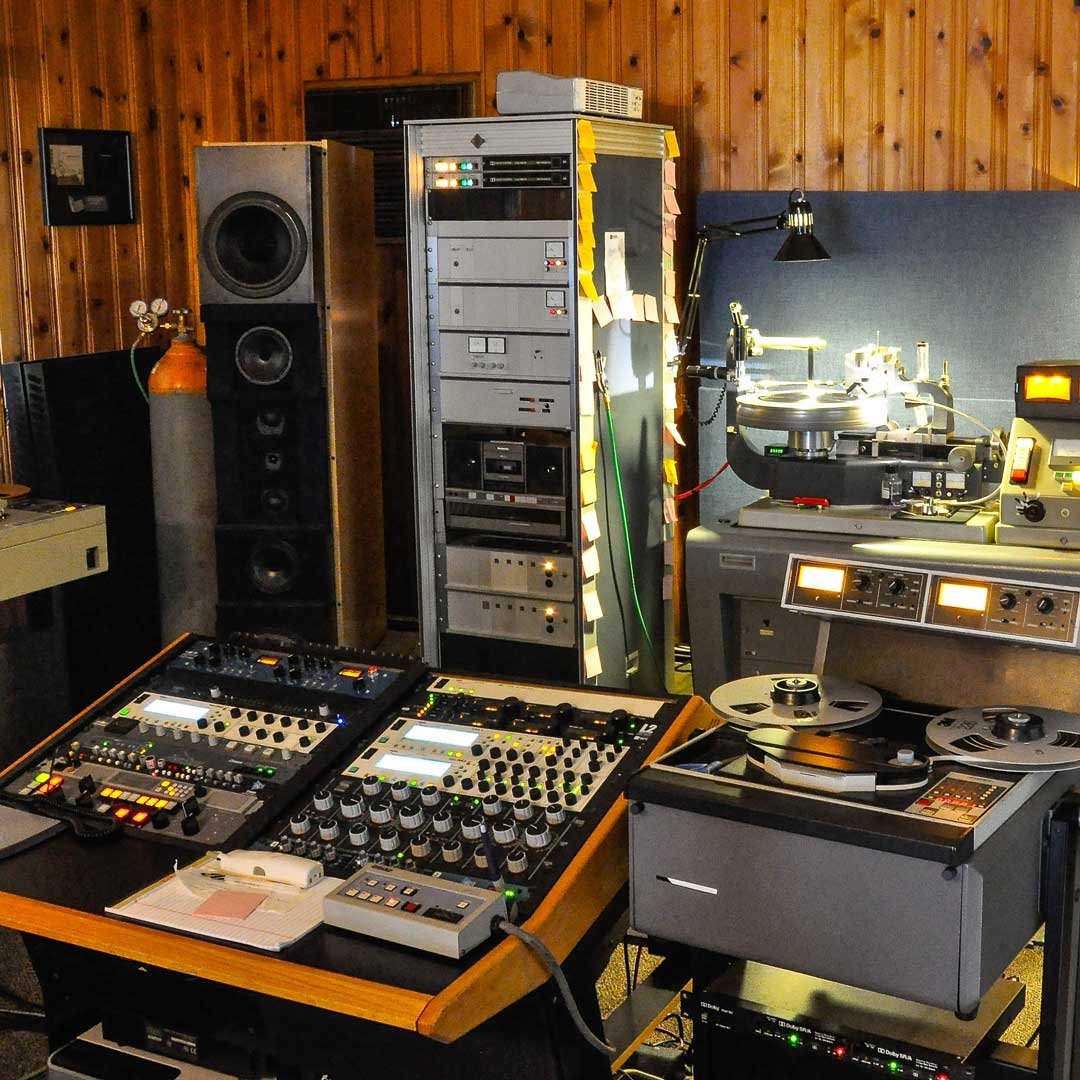 A professional DJ setup with turntables, audio mixer, speakers, and sound equipment in a room with wooden walls.