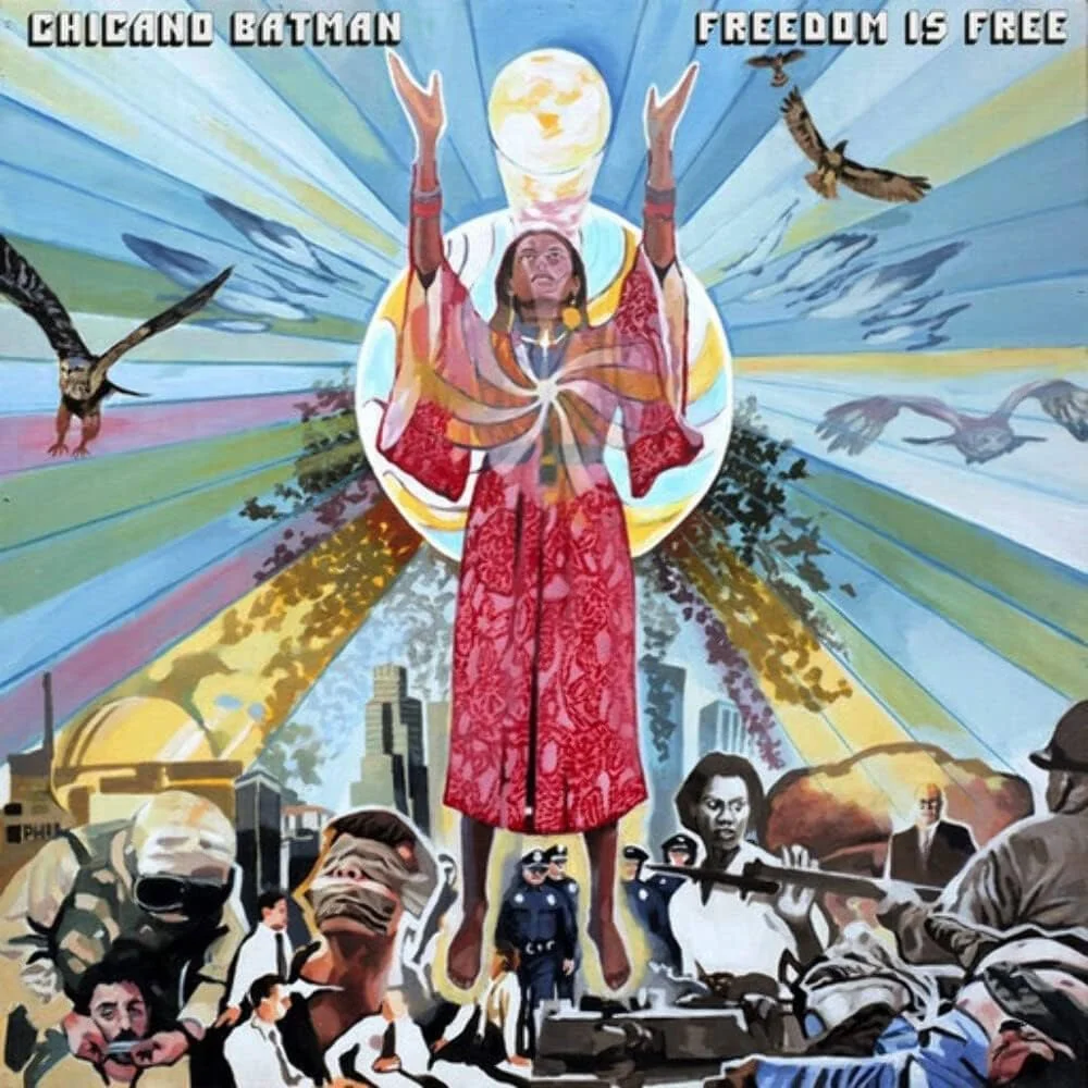 A mural depicting a woman with arms raised, enveloped in a circular shape with a glowing moon behind her head. The background features rays of color and flying birds, with the phrases 'Chicago Batman' and 'Freedom Is Free' at the top. Below, there are images of protests, police officers, and city buildings.