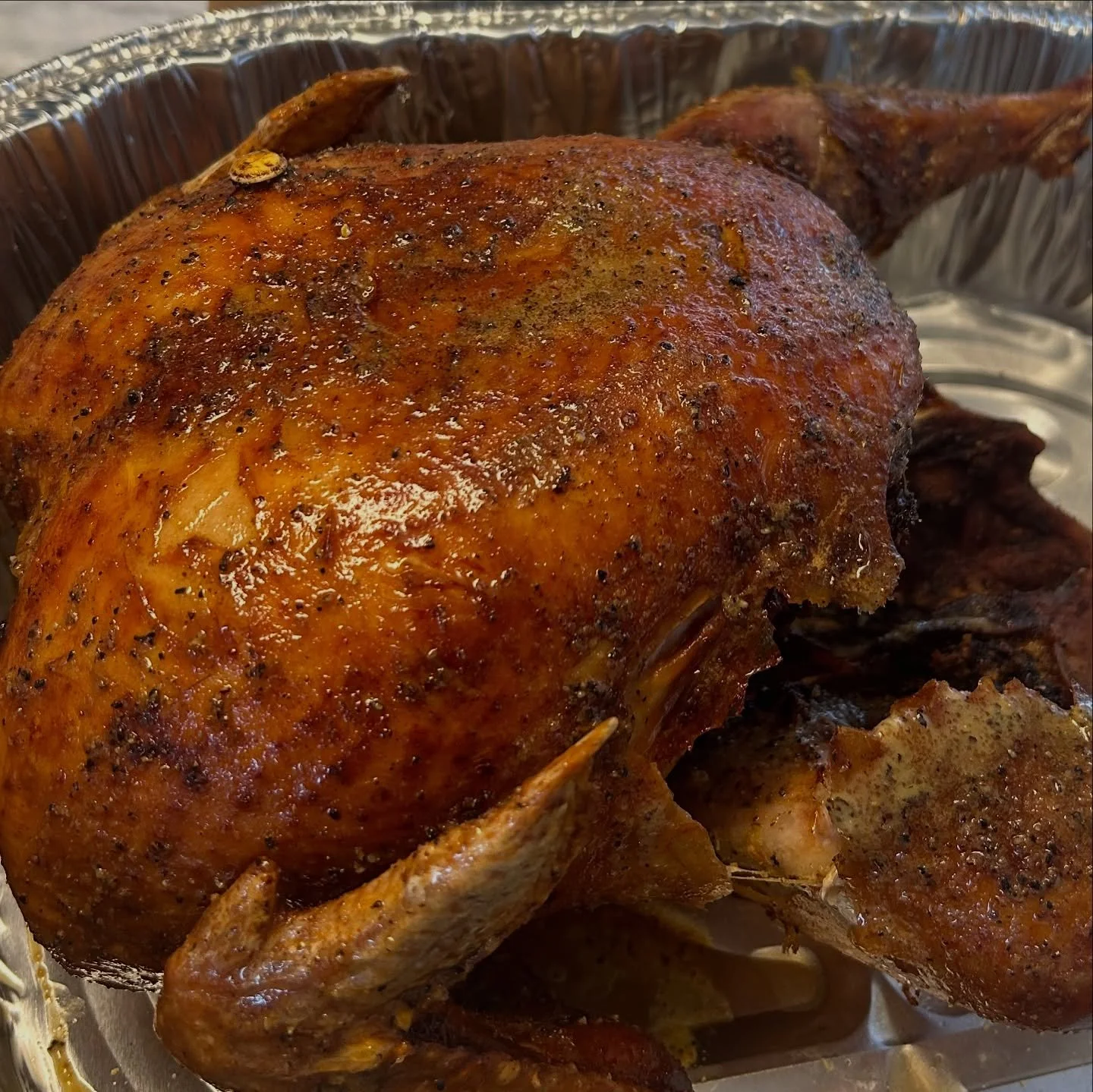 Roast chicken with crispy, seasoned skin in a foil-lined roasting pan.