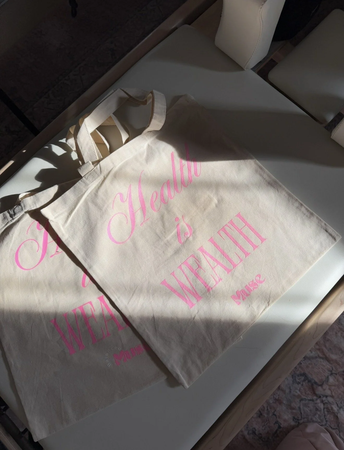 Reusable tote bag with pink text reading "Health is Wealth" on a white surface.