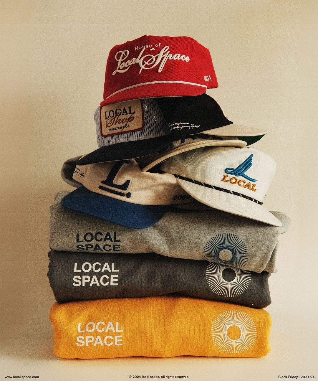 Stacked hats and sweatshirts with 'Local Space' logos, including baseball caps and beanies