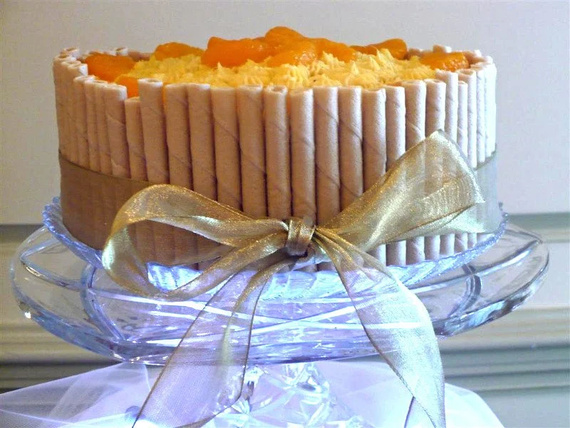MANGO BUTTERCREAM CAKE Truly a beautiful and delicious cake. Two white cake layers are separated by our own made- from-scratch mango buttercream, made with a combination of pureed mango and orange liqueur. After frosting, we surround the entire cake 