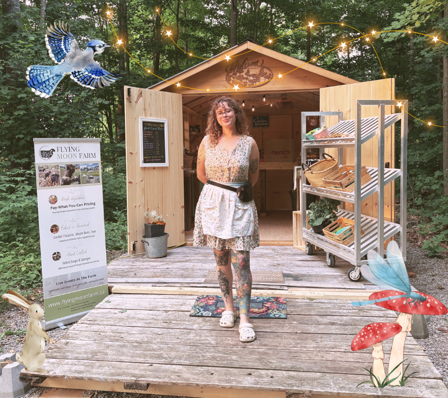 A woman with tattoos and glasses stands in front of a small wooden farm stand, smiling. The farm stand is set in a forested area at sunset, decorated with string lights and a bird perched on a shelf. There is a sign for 'Flying Moon Farm' next to her, advertising vegetables, baked goods, and soaps. Decorated mushrooms, a bunny, and a butterfly are digitally added around the scene.