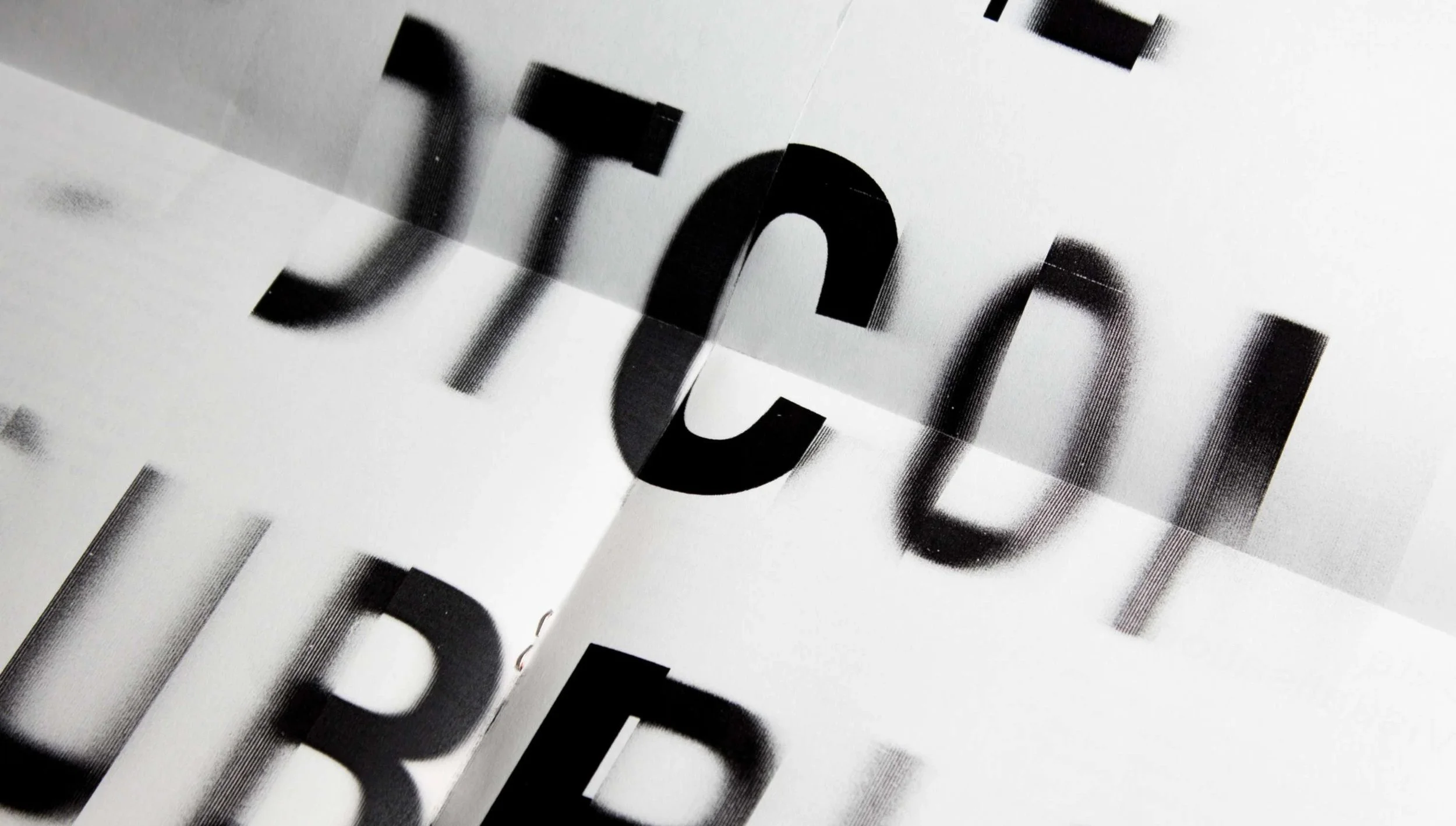 Close-up of black text on a white background, distorted with a halftone pattern creating a wavy, three-dimensional effect.