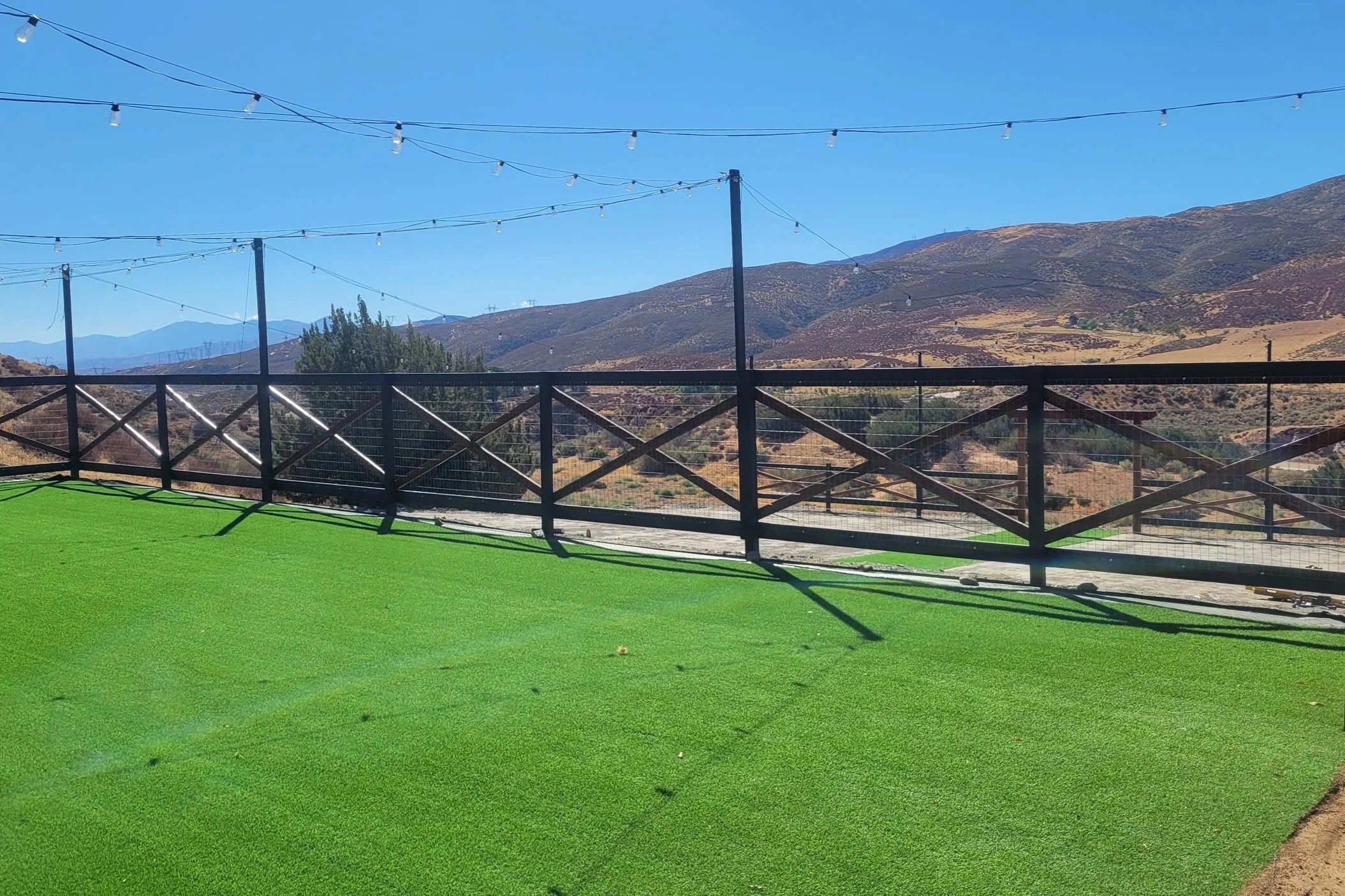 Yard transformation completed from a dirt pad, including regrading for proper drainage, installation of artificial turf, and construction of a new perimeter fence to create a clean, functional outdoor space.