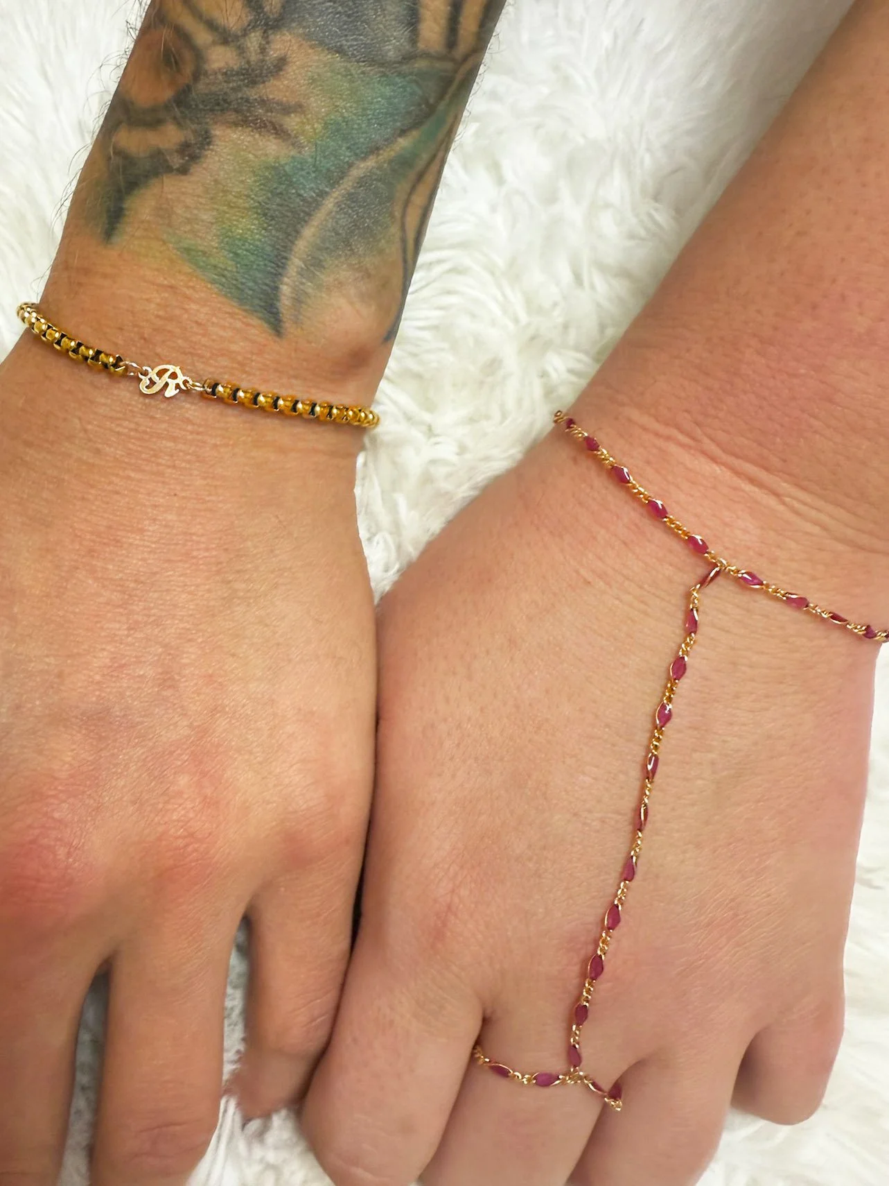 Two women's hands adorned with gold and pink beaded bracelets, showcasing a vibrant and stylish accessory combination