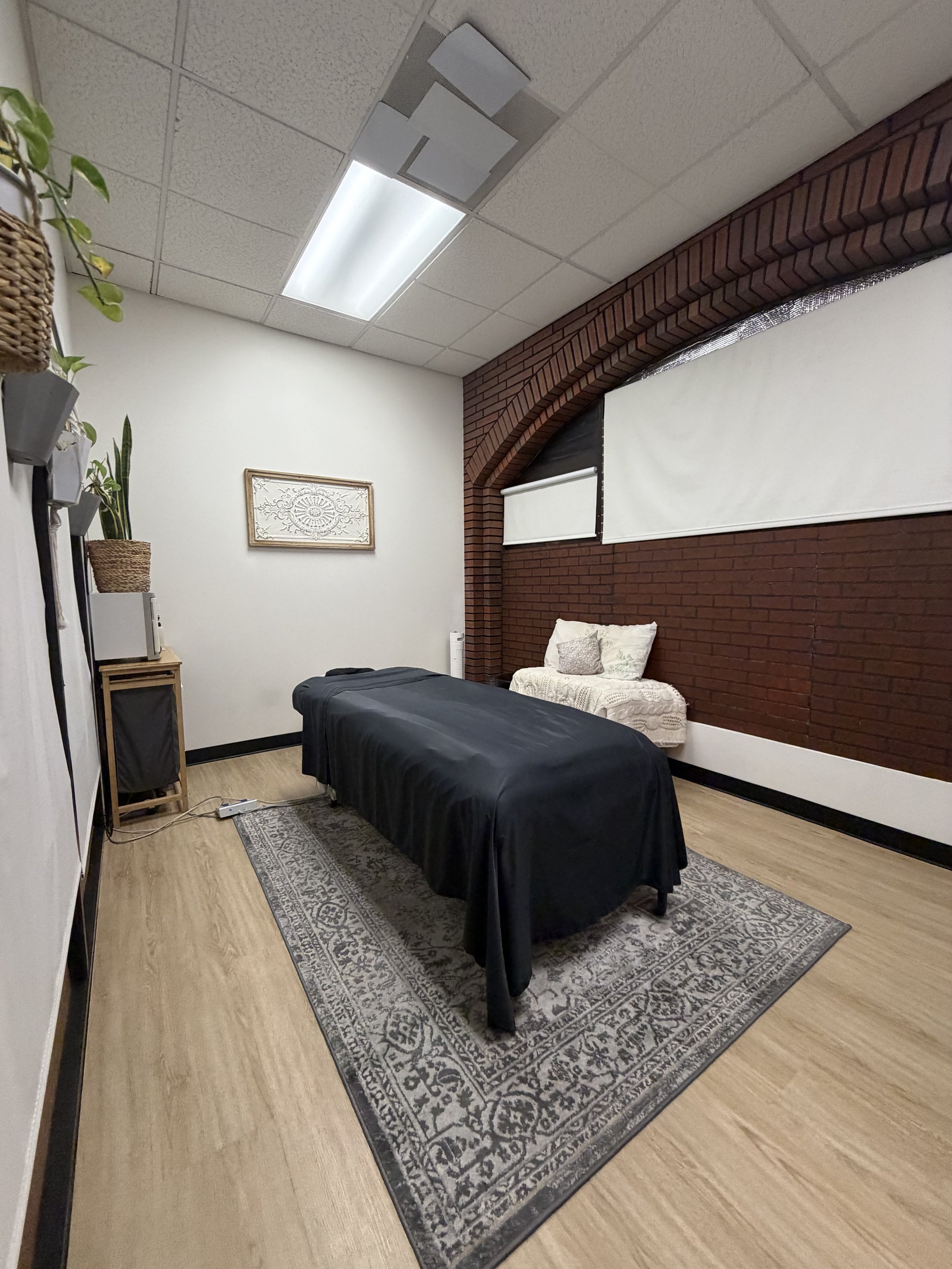 A serene massage room featuring a black blanket spread on the floor, creating a calming atmosphere for relaxation.