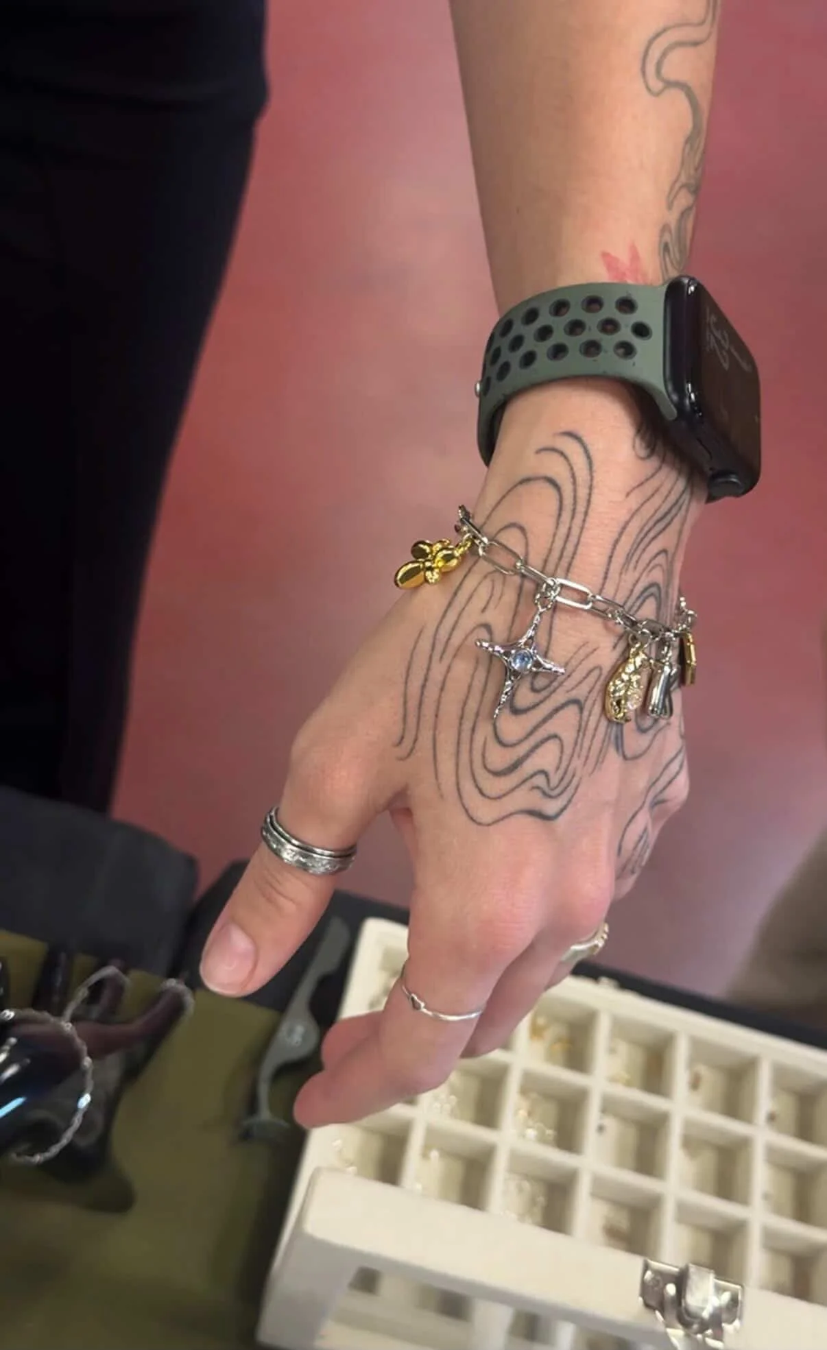 A close-up of a wrist adorned with tattoos and a stylish watch, showcasing personal expression and fashion.