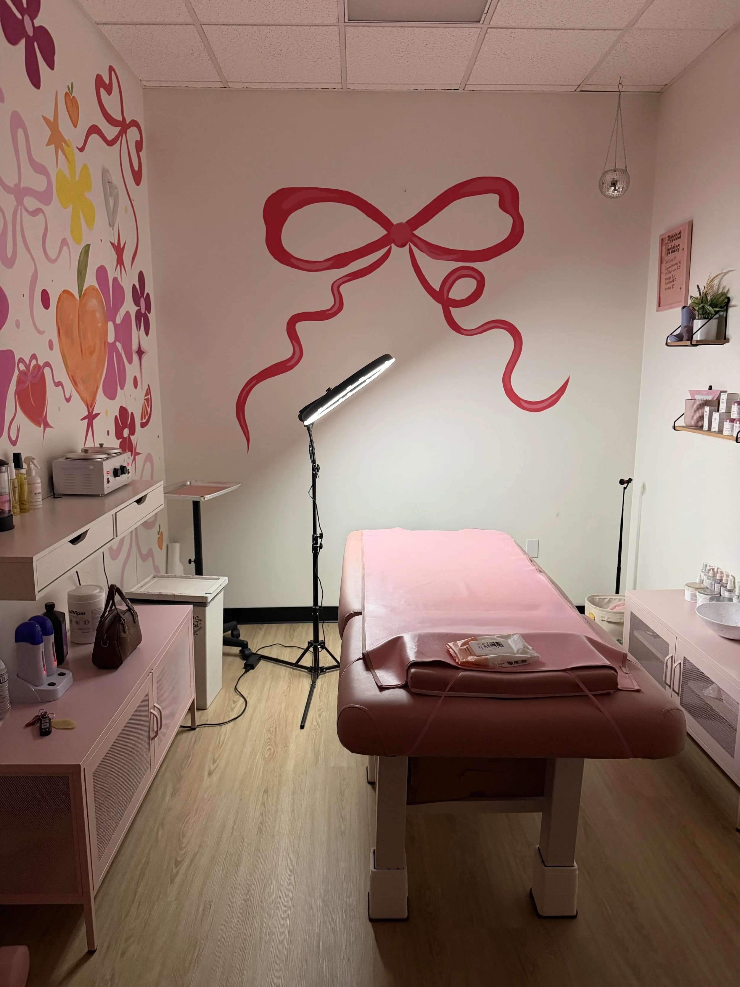 A cozy room featuring a pink bed and a large decorative bow on the wall, creating a playful atmosphere.