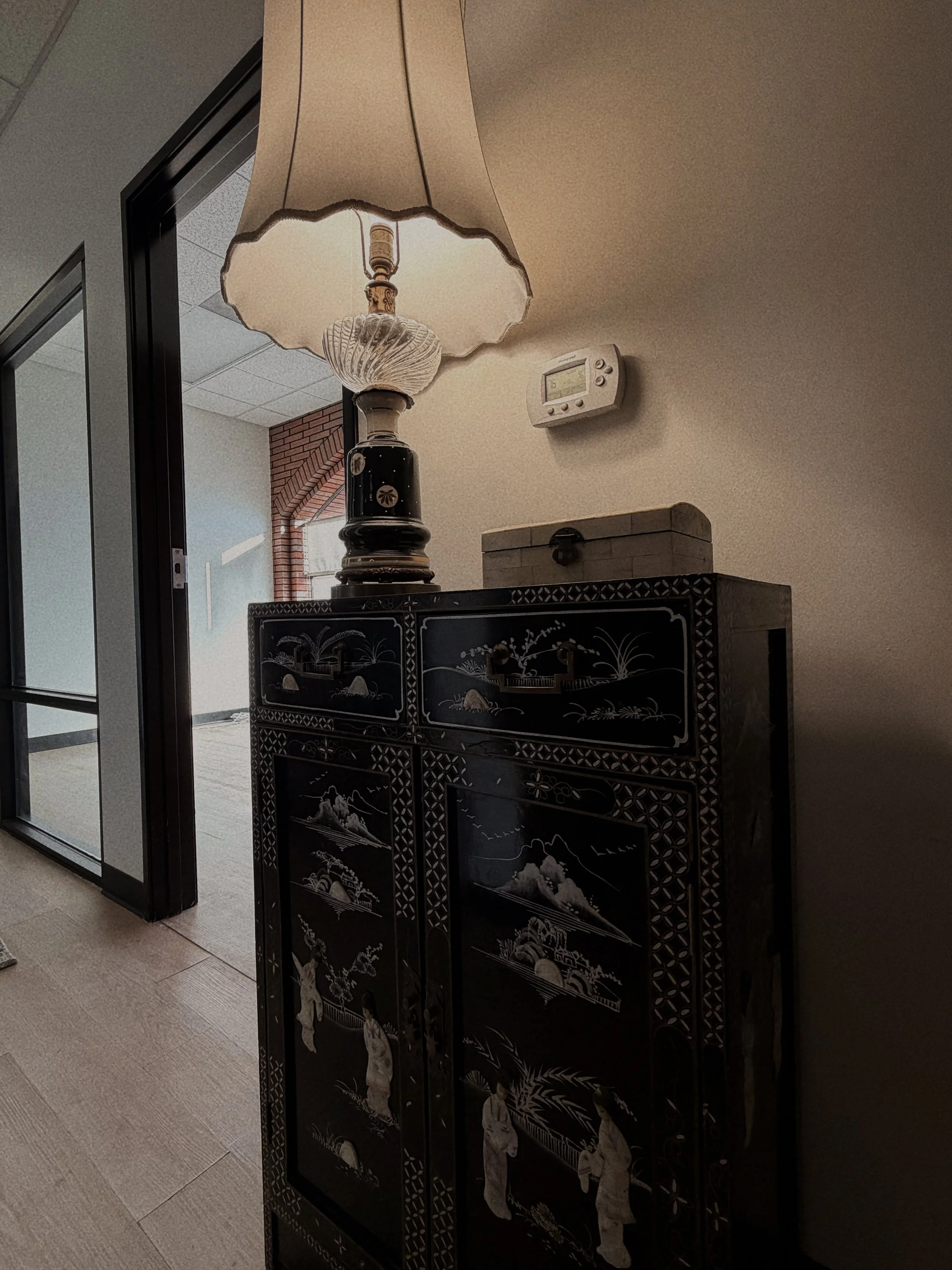 A lamp placed on top of a wooden cabinet, providing ambient light in a cozy room setting.