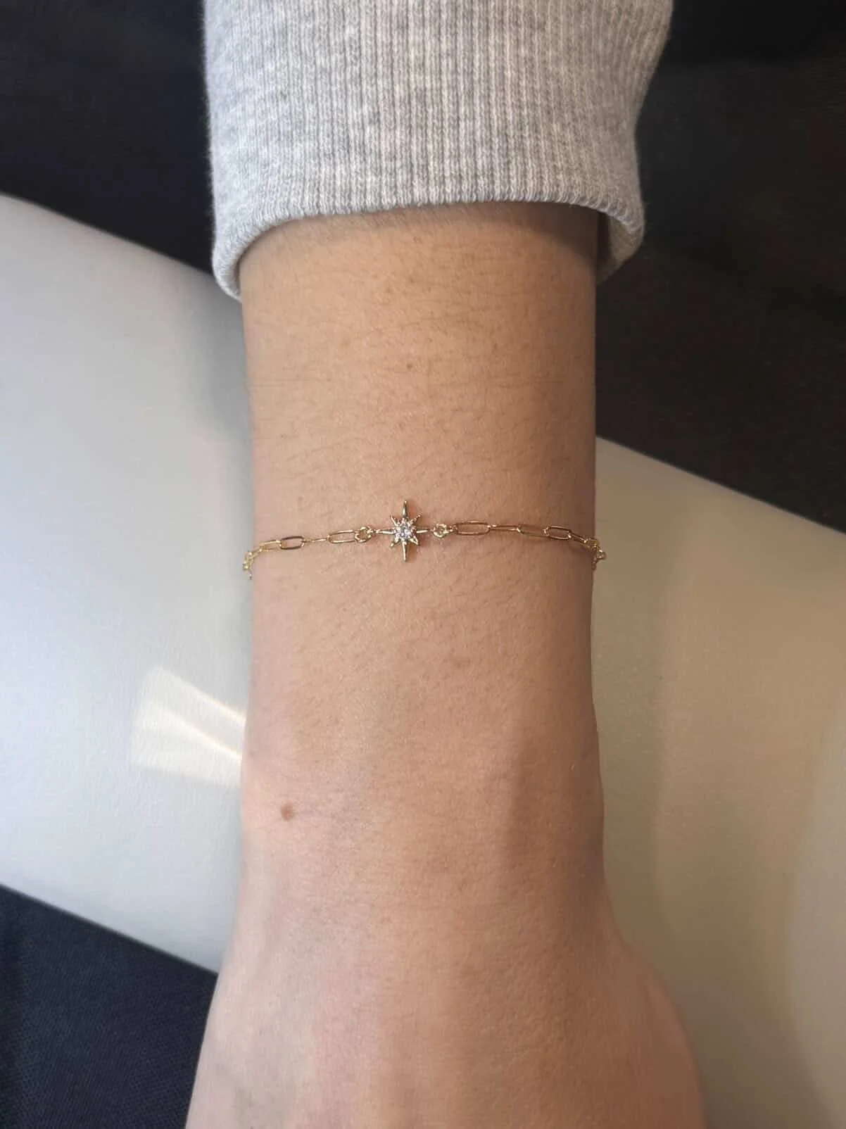 A close-up of a woman's wrist adorned with a gold bracelet featuring a star charm.