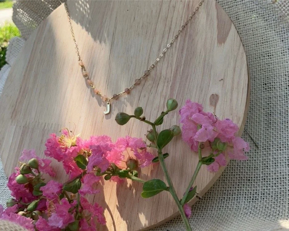 A heart-shaped necklace rests on a wooden plate, showcasing its elegant design against the natural texture of the wood