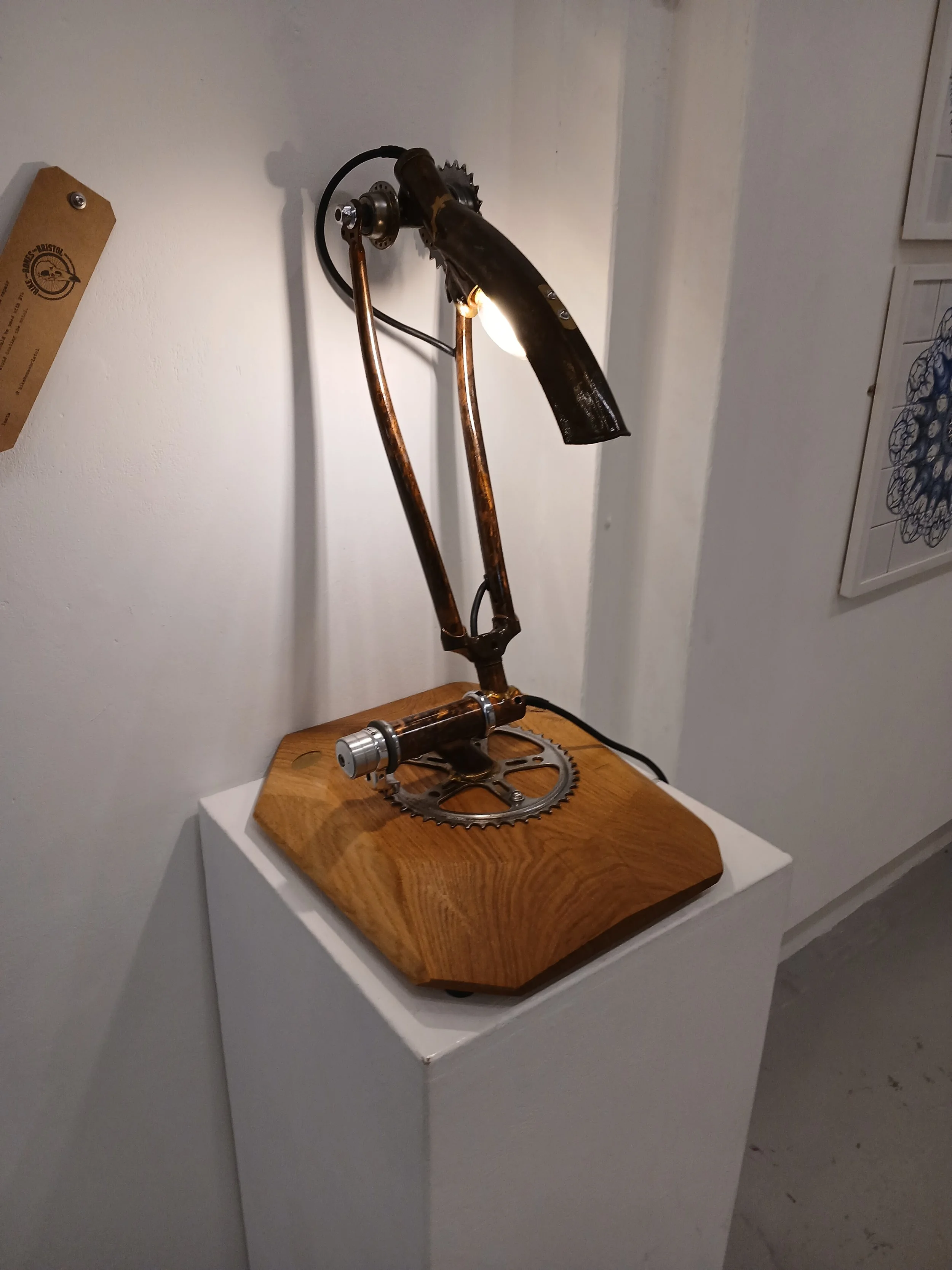 A lamp made from bicycle parts, mounted on a wooden base.