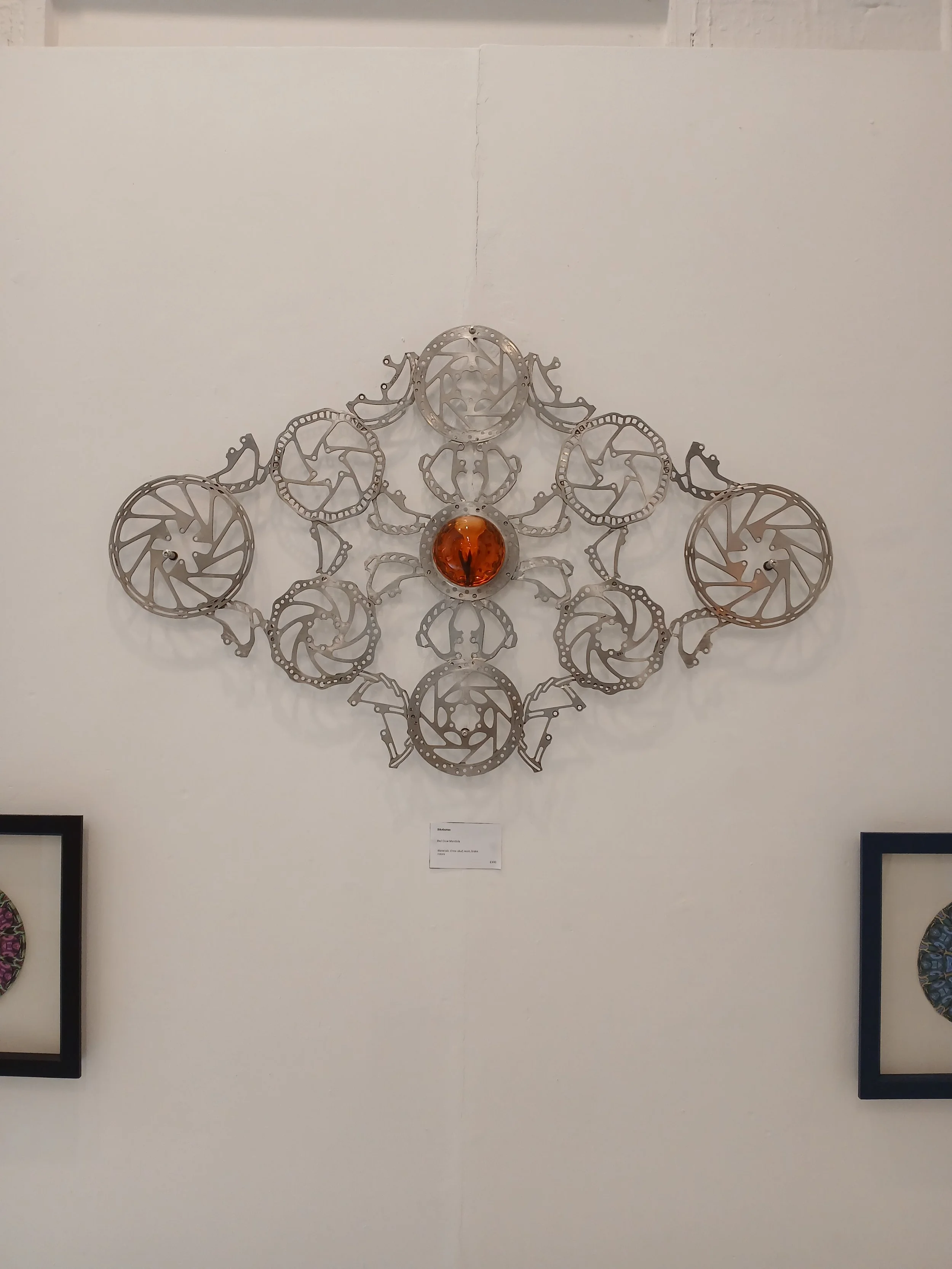 A wall-mounted art piece made of multiple interconnected skateboard decks with a central orange glass sphere.