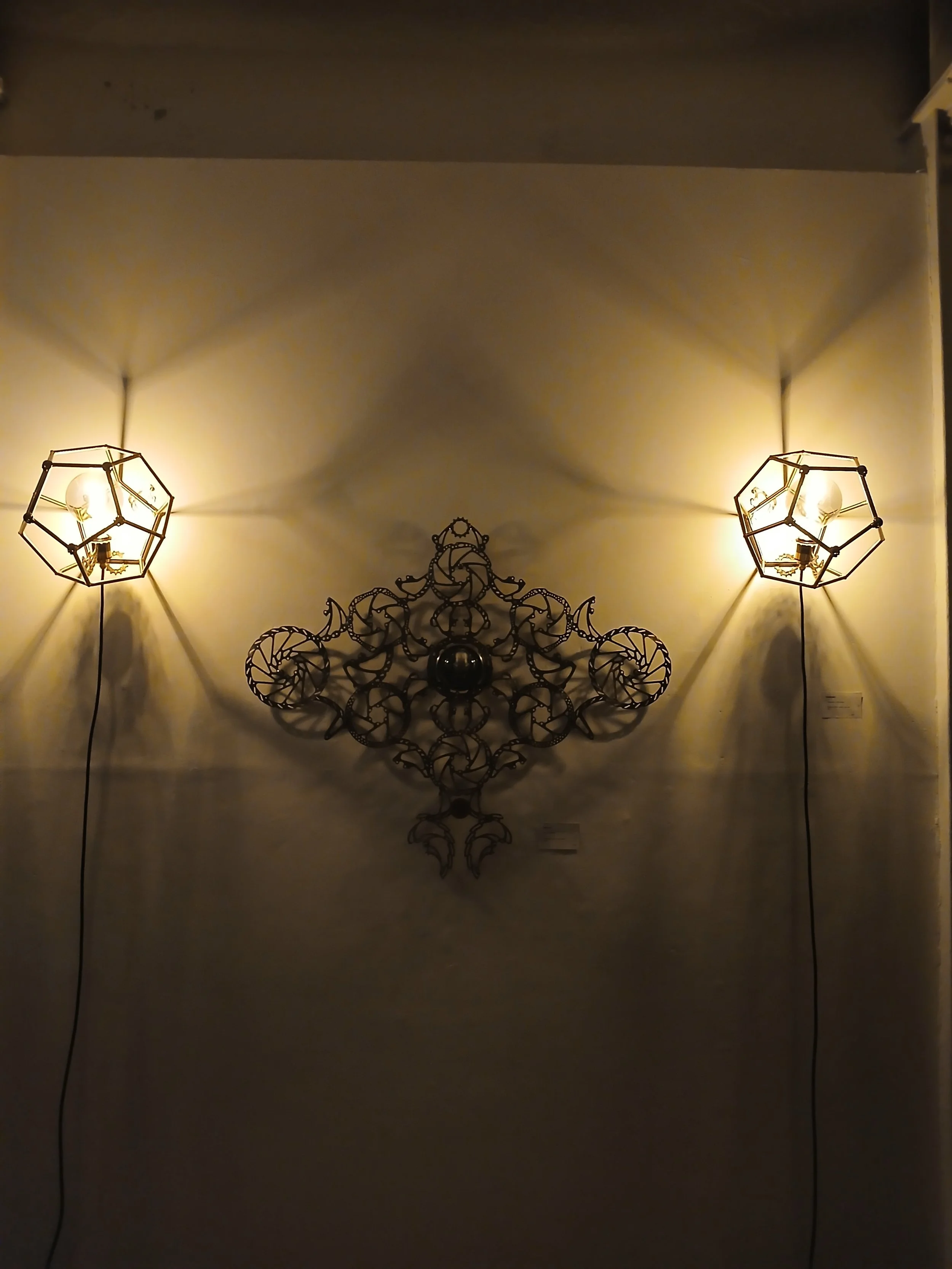 Wall-mounted decorative art piece with two dodecaedron skull lamps on the sides projecting geometrical shadows
