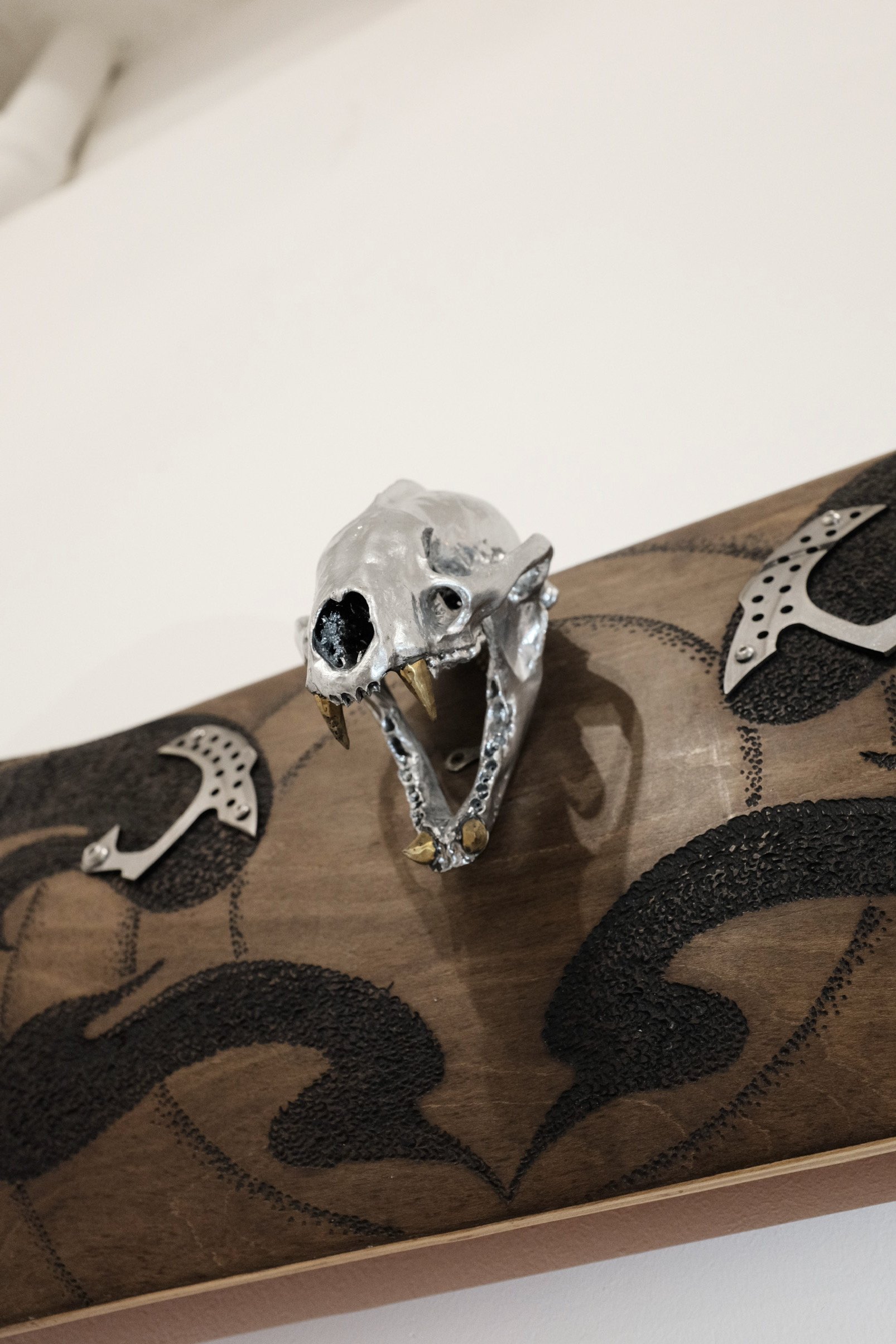 Decorative skull with gold teeth mounted on a wooden surface with black and silver designs.